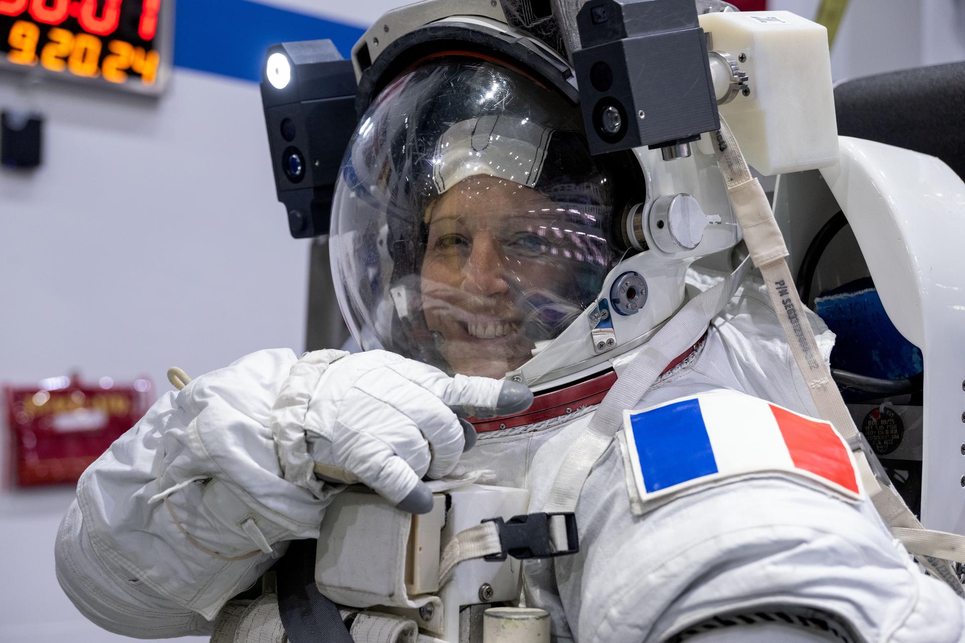 ESA (European Space Agency) astronaut Sophie Adenot points to her home country's flag patch representing France attached to her spacesuit during a spacewalk training session at the Johnson Space Center's Neutral Buoyancy Laboratory in Houston, Texas.