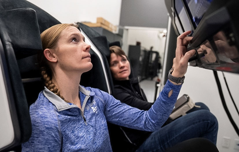 From left, NASA astronauts Nichole Ayers, pilot, and Anne McClain, commander train inside a mockup of a Dragon cockpit at the company's facilities in Hawthorne, California. Credit: SpaceX