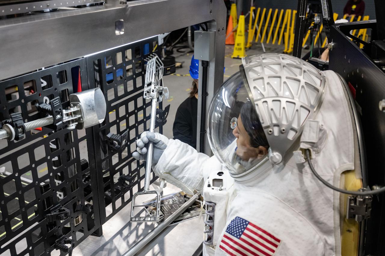 NASA astronaut Jessica Meir grabs a lunar geology tool from a tool rack on Lunar Outpost’s Eagle lunar terrain vehicle during testing at NASA’s Johnson Space Center. Image Credit: NASA/James Blair
