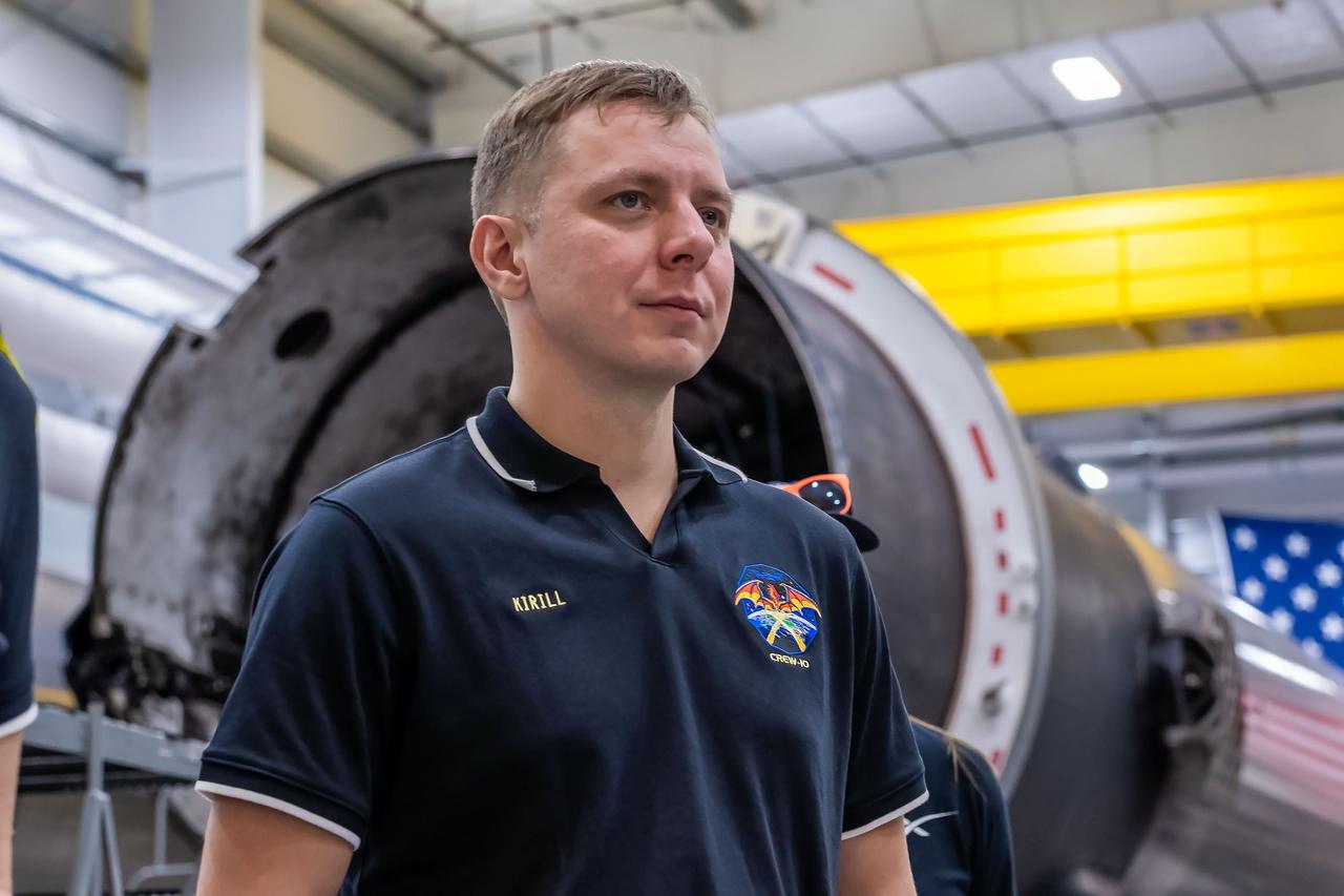 jsc2024e080750 (Nov. 18, 2024) --- NASA’s SpaceX Crew-10 Mission Specialist Kirill Peskov of Roscosmos stands in front of a Falcon 9 first-stage booster at SpaceX’s HangarX facility at NASA's Kennedy Space Center in Florida. Credit: SpaceX