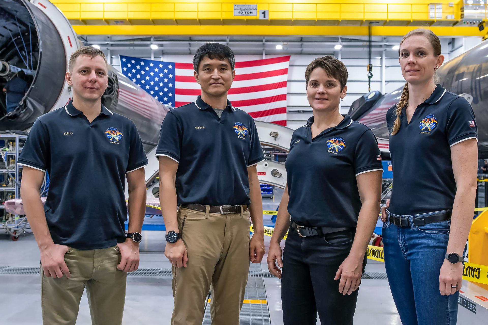 Các thành viên SpaceX Crew-10 của NASA đứng giữa các tên lửa đẩy giai đoạn đầu của Falcon 9 tại cơ sở HangarX của SpaceX tại Trung tâm vũ trụ Kennedy của NASA ở Florida. Từ trái sang phải là Chuyên gia sứ mệnh Kirill Peskov của Roscosmos, Chuyên gia sứ mệnh Takuya Onishi của JAXA (Cơ quan thám hiểm hàng không vũ trụ Nhật Bản), cùng với Chỉ huy phi hành gia NASA Anne McClain và Phi công Nichole Ayers.