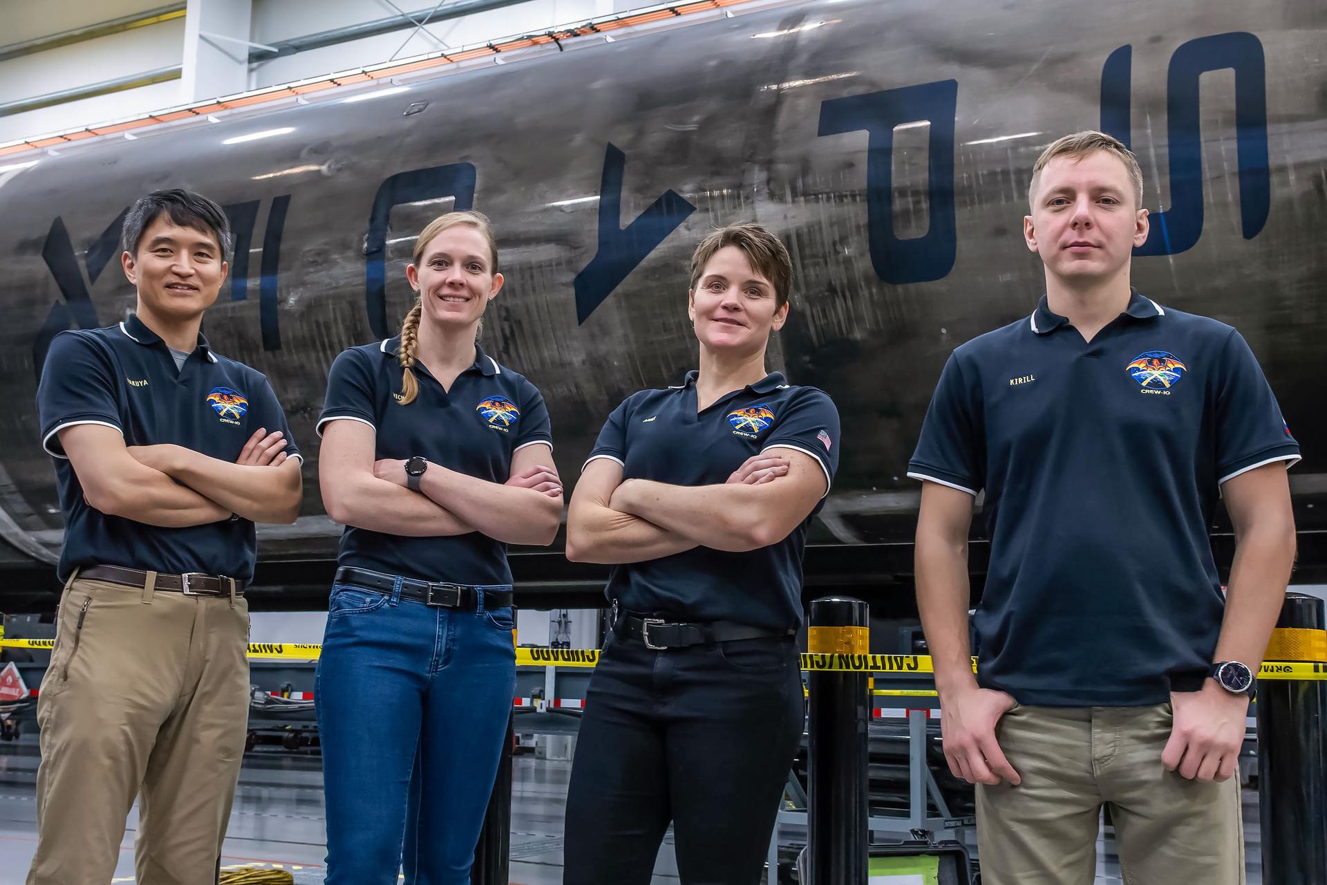 NASA’s SpaceX Crew-10 members stand in front of a Falcon 9 first-stage booster at SpaceX’s HangarX facility at NASA's Kennedy Space Center in Florida. From left are Mission Specialist Takuya Onishi of JAXA (Japan Aerospace Exploration Agency), Commander Anne McClain of NASA, Pilot Nichole Ayers of NASA, and Mission Specialist Kirill Peskov of Roscosmos.
