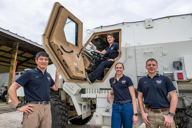 NASA image: SpaceX Crew-10 members pose in front of their Mine Resistant Ambush Protected (MRAP) vehicle