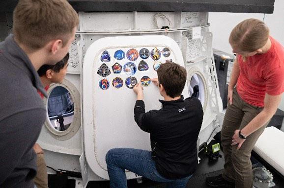 jsc2025e011332 (Feb. 24, 2025) --- NASA astronaut and commander of NASA's SpaceX Crew-10 mission Anne McClain places the Crew-10 mission patch sticker on the Dragon training hatch at the company’s facility in Hawthorne, California. Credit: SpaceX