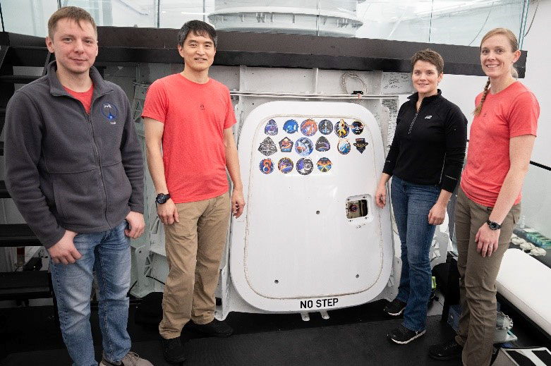NASA's SpaceX Crew-10 crewmembers pose for a portrait in front of the Crew-10 patch at the company’s facility in Hawthorne, California. From left are Mission Specialist Kirill Peskov of Roscosmos, Mission Specialist Takuya Onishi of JAXA (Japan Aerospace Exploration Agency), Commander Anne McClain of NASA, and Pilot Nichole Ayers of NASA.