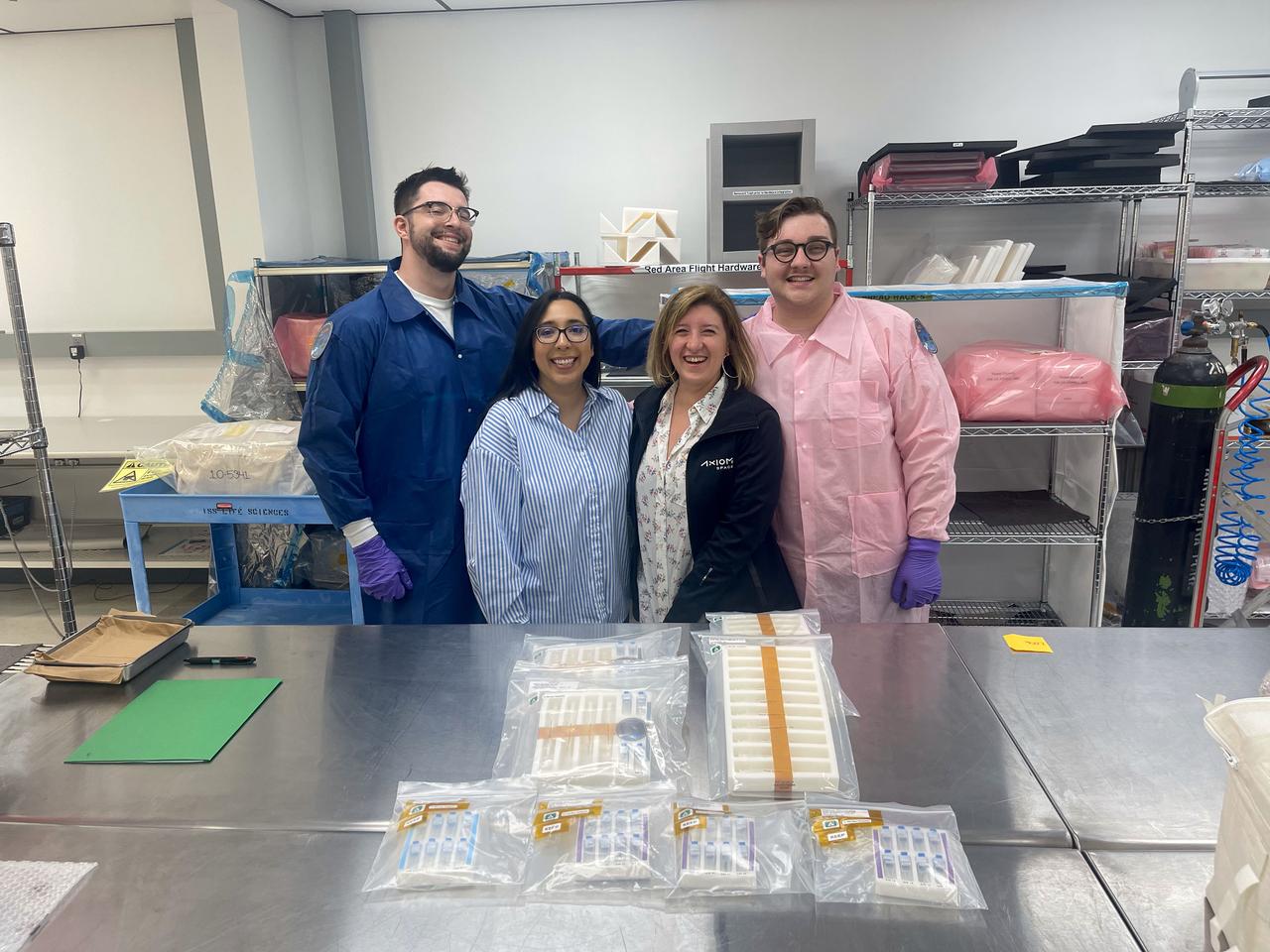 jsc2025e036193 (4/4/2025) --- Our team is pictured turning over samples for SpX-30 (Demo 2) to the NASA Packaging team. From left to right, we see Maxwell Landolina (UCONN PhD Student), Alexis Rios (Payload Mission Integrator, Axiom Space), Pinar Mesci (Senior Program Manager, Axiom Space), and Trystin Cote (UCONN PhD Student).