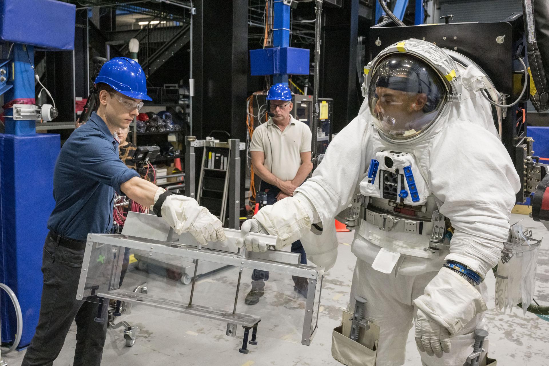 Trevor Graff, the Artemis Science Team Hardware and Testing Lead, handles the Lunar Environment Monitoring Station (LEMS) mass mockup during testing with the Active Response Gravity Offload System (ARGOS) at Johnson Space Center in Houston, Texas on April 21st, 2025. LEMS is a compact, autonomous, and self-sustaining seismometer suite designed to carry out continuous, long-term, monitoring of the lunar seismic environment at the South Polar region. Photo Credit: NASA/ James Blair