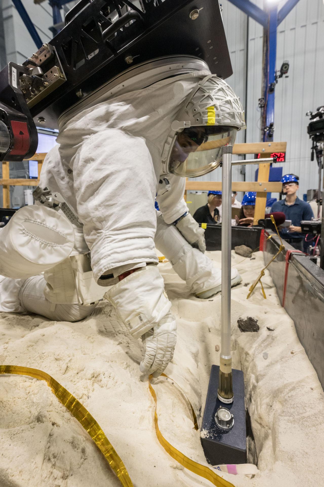Trevor Graff, the Artemis Science Team Hardware and Testing Lead, deploys a mockup of the Lunar Environment Monitoring Station (LEMS) during testing with the Active Response Gravity Offload System (ARGOS) at Johnson Space Center in Houston, Texas on April 21st, 2025. LEMS is a compact, autonomous, and self-sustaining seismometer suite designed to carry out continuous, long-term, monitoring of the lunar seismic environment at the South Polar region. Photo Credit: NASA/ James Blair