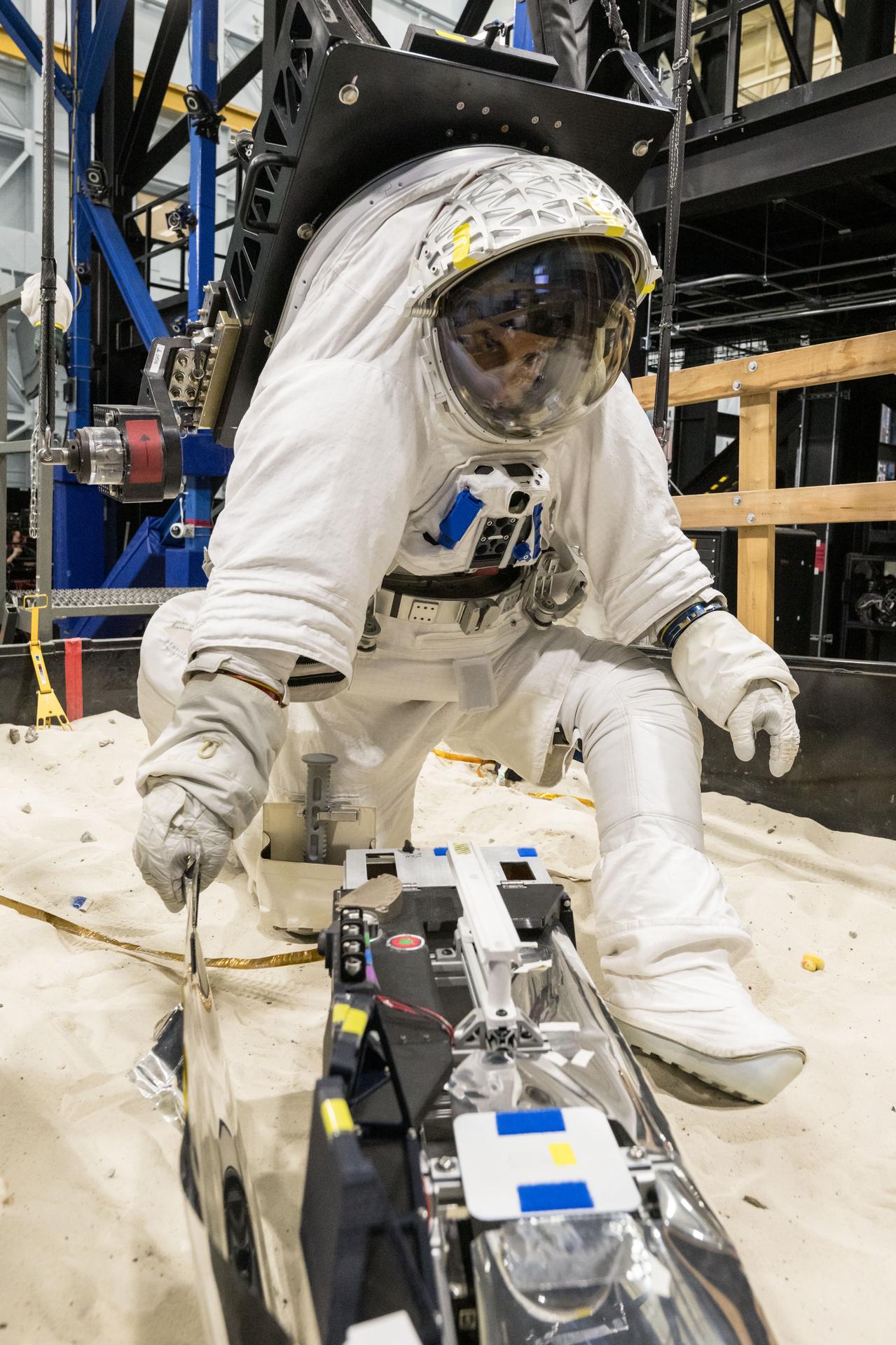 Trevor Graff, the Artemis Science Team Hardware and Testing Lead, deploys a mockup of the Lunar Environment Monitoring Station (LEMS) during testing with the Active Response Gravity Offload System (ARGOS) at Johnson Space Center in Houston, Texas on April 21st, 2025. LEMS is a compact, autonomous, and self-sustaining seismometer suite designed to carry out continuous, long-term, monitoring of the lunar seismic environment at the South Polar region. Photo Credit: NASA/ James Blair