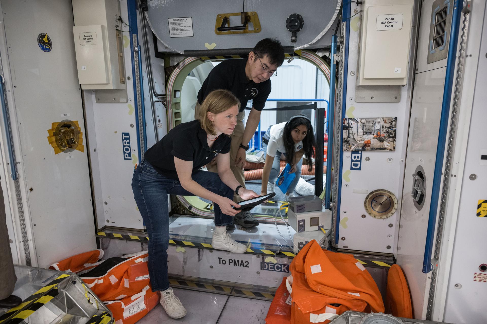 NASA astronaut Zena Cardman (front) and JAXA (Japan Aerospace Exploration Agency) astronaut Kimiya Yui participate in a training simulation inside a mockup at NASA’s Johnson Space Center in Houston, Texas, along with their Expedition 74 crewmates (not shown).