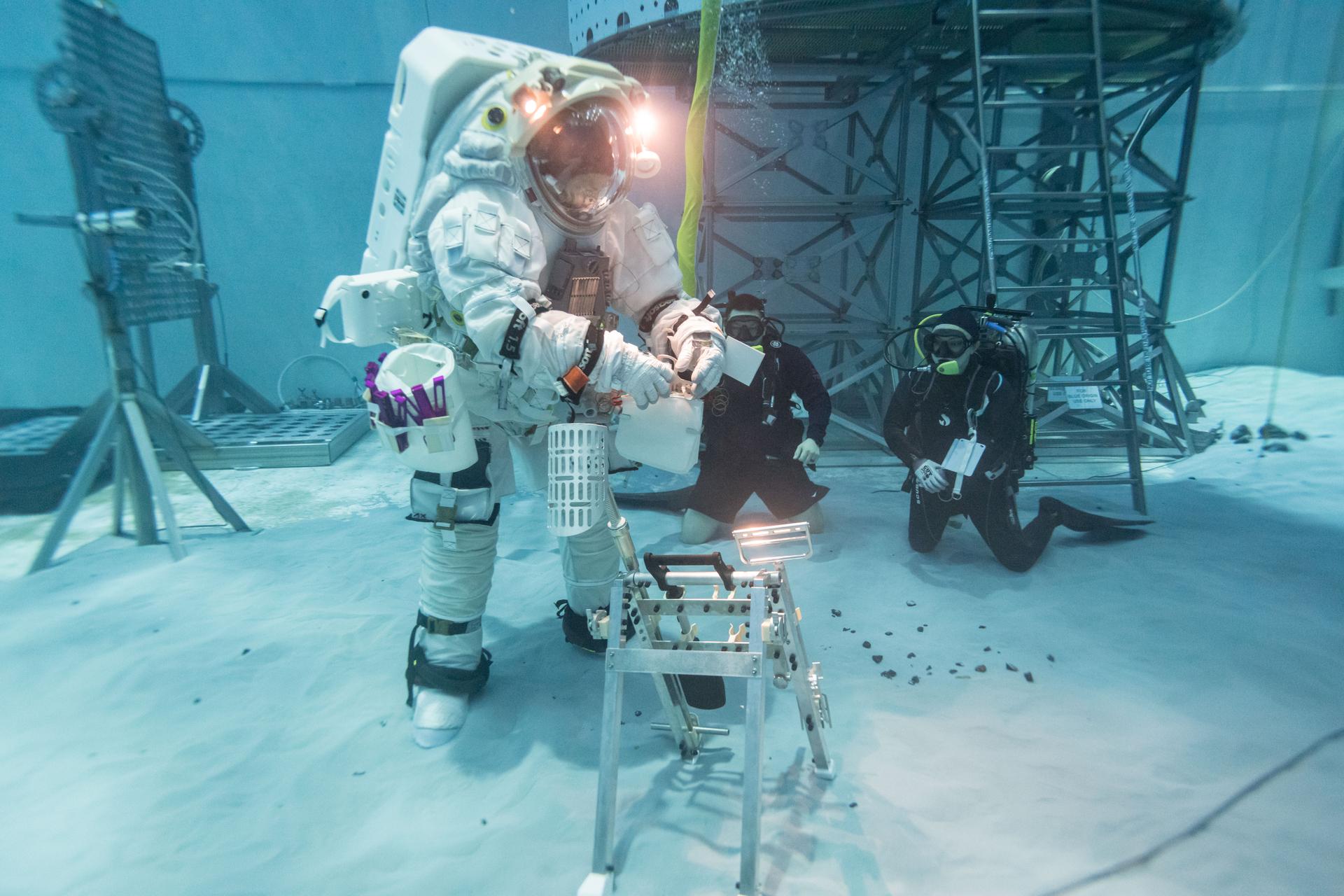 A NASA crew member practices simulated lunar surface operations at NASA’s Neutral Buoyancy Laboratory where teams evaluate how well crew perform tasks while wearing the Artemis III lunar spacesuit developed by Axiom Space called the AxEMU (Axiom Extravehicular Mobility Unit). 