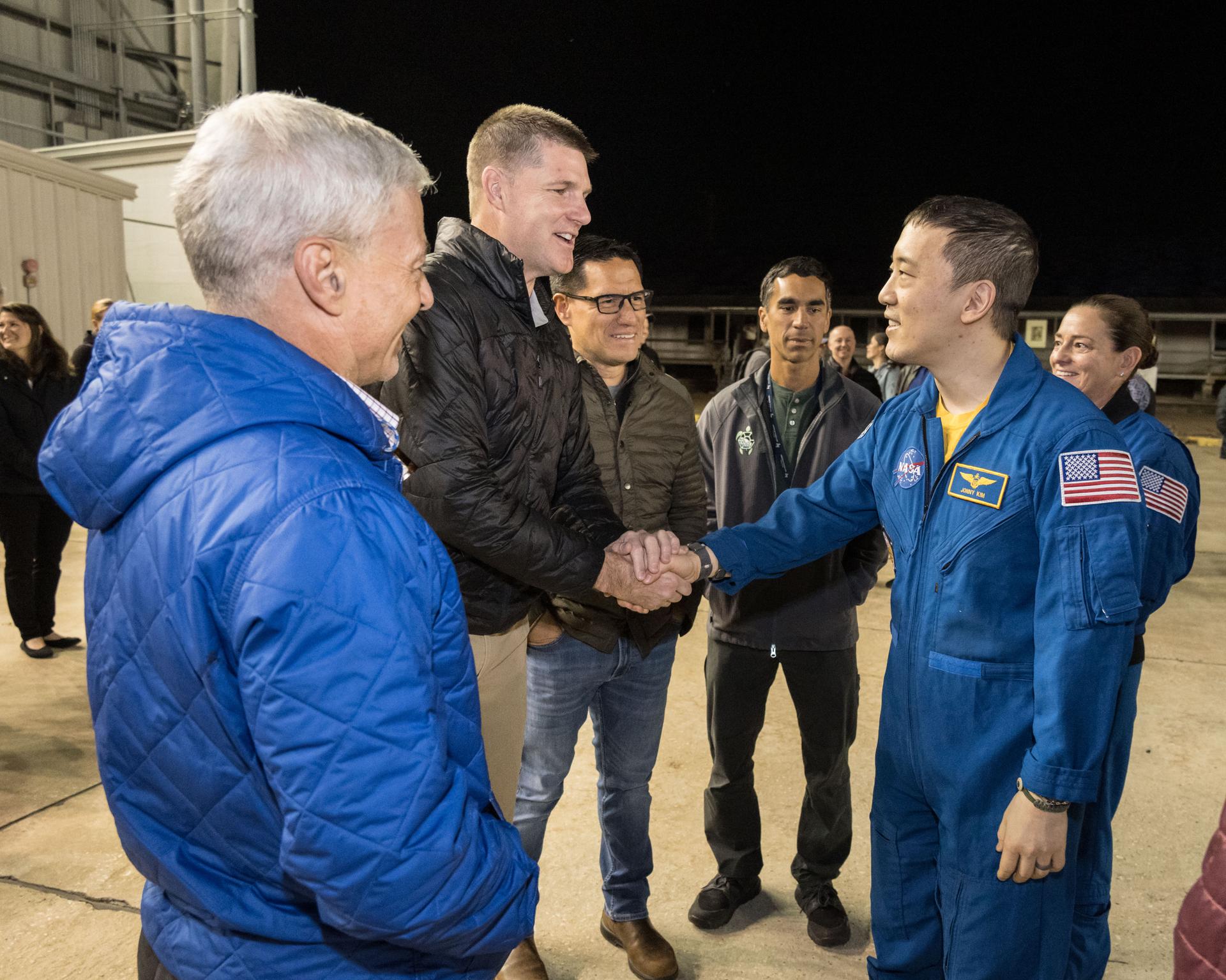 NASA astronaut Jonny Kim—shaking the hand of Canadian Space Agency astronaut and Artemis II crew member Jeremy Hansen—is pictured at Ellington Field in Houston, Texas. The day before, Kim had landed in Kazakhstan aboard the Soyuz MS-27 crew spacecraft with Roscosmos cosmonauts Sergey Ryzhikov and Alexey Zubritsky after completing a 245-day research mission aboard the International Space Station. Surrounding Kim (from left) are NASA astronauts Mark Vande Hei, Mark Rubio, Raja Chari, and Nicole Mann.