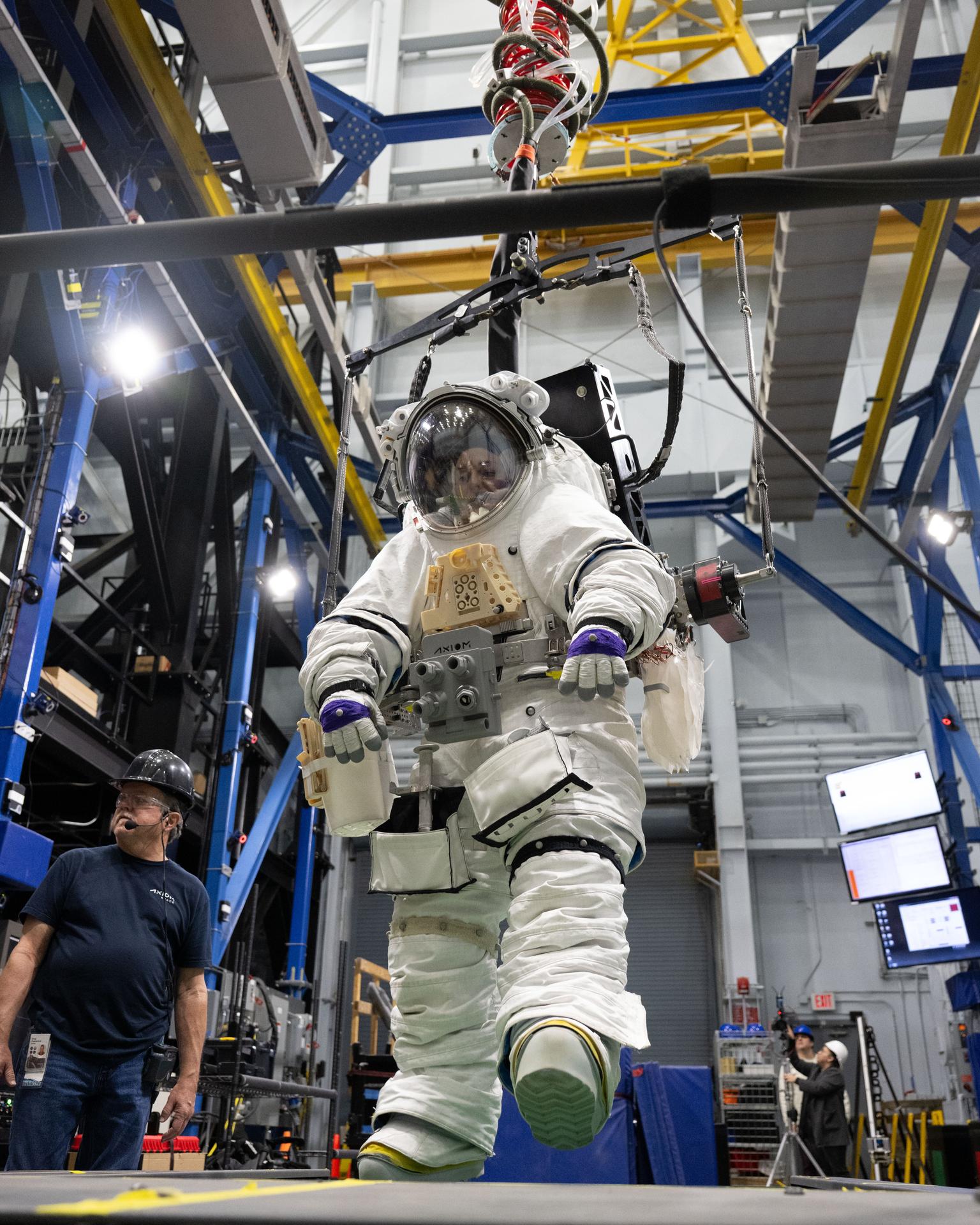 A NASA crew member practices simulated lunar surface operations at NASA’s Johnson Space Center during an elevated suit pressure test where teams evaluate how well crew perform tasks in different suit pressure levels while wearing the Artemis III lunar spacesuit developed by Axiom Space called the AxEMU (Axiom Extravehicular Mobility Unit).