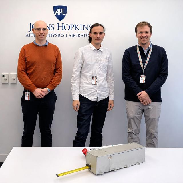 jsc2026e014327 (March 23, 2026) --- The research team as part of the Nanoracks-ITSI investigation, from left: Alex Chartier (PI), Matt Bailey (engineer), Greg Merboth (engineer). This investigation aims to measure radio signals that have passed through the ionosphere in order to quantify the effects of atmospheric dynamics on propagation. Earth’s ionosphere is highly variable due to forcing by the lower atmosphere, the aurora, meteors, and the Sun among other factors. This variability has important effects on radio propagation, and accurate characterization may support efforts to mitigate its effects on technology such as radar. Credit: Johns Hopkins Applied Physics Laboratory.