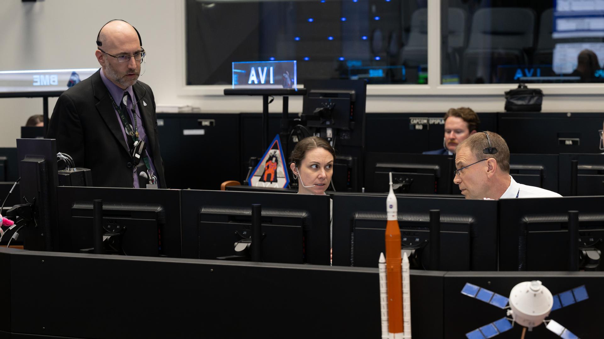 jsc2026e018915 (April 1, 2026) - Artemis II lead capcom Stan Love (right) and Artemis II chief training officer Jacki Mahaffey (middle) have a conversation in Mission Control's White Flight Control Room at NASA's Johnson Space Center during launch and ascent on Wednesday, April 1, 2026.
