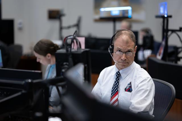 Artemis II capcom Stan Love sits on console in Mission Control Room.