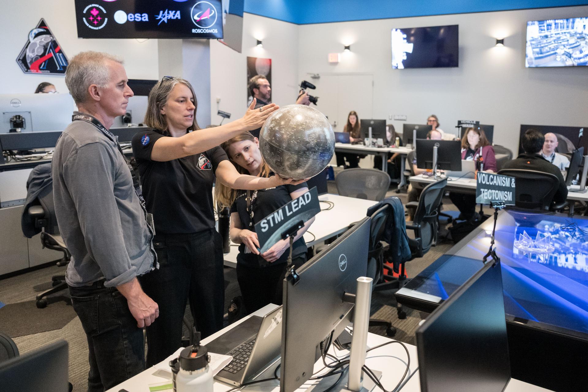 Artemis II lunar science team members, from left, Ryan Ewing, Juliane Gross, and Debra Needham, discuss lunar geography ahead of the translunar injection burn that accelerated the Orion spacecraft to break free of Earth’s orbit and began the outbound trajectory toward the Moon. They are in the Science Evaluation Room (SER) a back room that supports lunar science and planetary observations for the Artemis science officer in the mission’s main flight control room. Built specifically for Artemis missions with these science priorities in mind, the SER is equipped to support rapid data interpretation, collaborative analysis, real-time decision making, and seamless coordination between the science and operations teams.