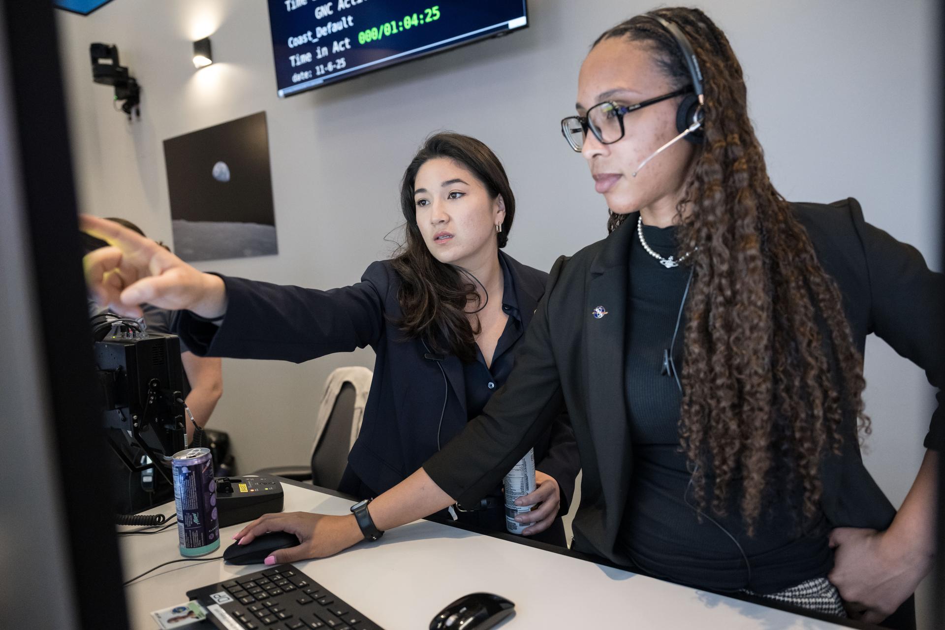 Artemis science officer, Angela Garcia, left and lunar science team member, Kiarre Dumes discuss science operations in the Science Evaluation Room (SER) in Mission Control at NASA's Johnson Space Center in Houston. The SER supports lunar science and planetary observations for the Artemis science officer in the mission’s main flight control room. Dumes serves as the SERCOMM, or Science Evaluation Room Communicator, acting as the singular voice from the science team in the back room, reporting to the science officer. Credits: NASA/Luna Posadas Nava