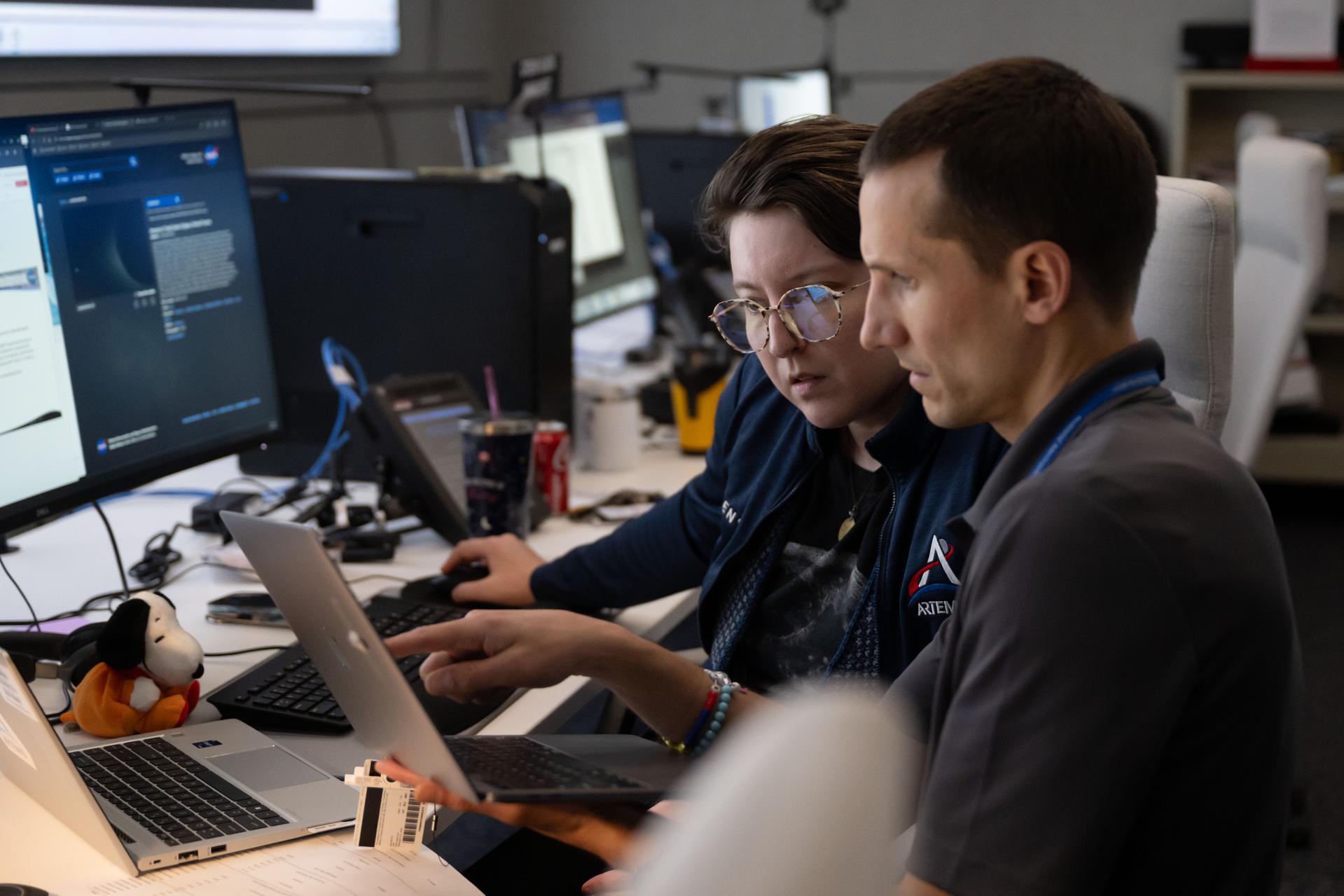 Artemis lunar science team members, from left, Alexandra Constantinou, and David Hollibaugh-Baker, work in the Science Mission Operations Room at NASA’s Johnson Space Center in Houston. They are analyzing imagery and audio recordings of lunar observations captured by the Artemis II astronauts during their lunar flyby on April 6, 2026. 
