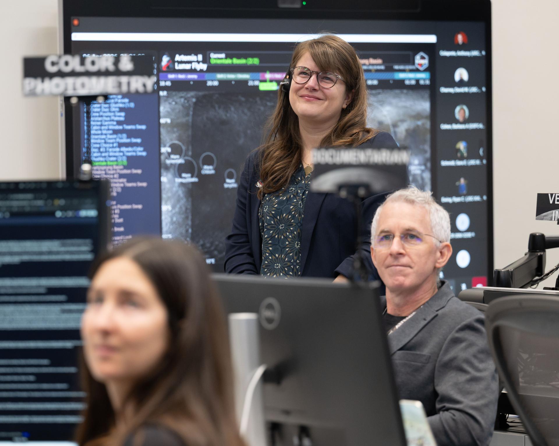 Artemis II deputy lunar science lead Marie Henderson, background, and lunar science team members, Ariel Deutsch, and Ryan Ewing, react to crew observations during the lunar flyby on April 6, 2026.  The team worked in the Science Evaluation Room (SER) in Mission Control at NASA’s Johnson Space Center in Houston. Built specifically for Artemis missions with these science priorities in mind, the SER is equipped to support rapid data interpretation, collaborative analysis, real-time decision making, and seamless coordination between the science and operations teams. Credits: NASA/Luna Posadas Nava