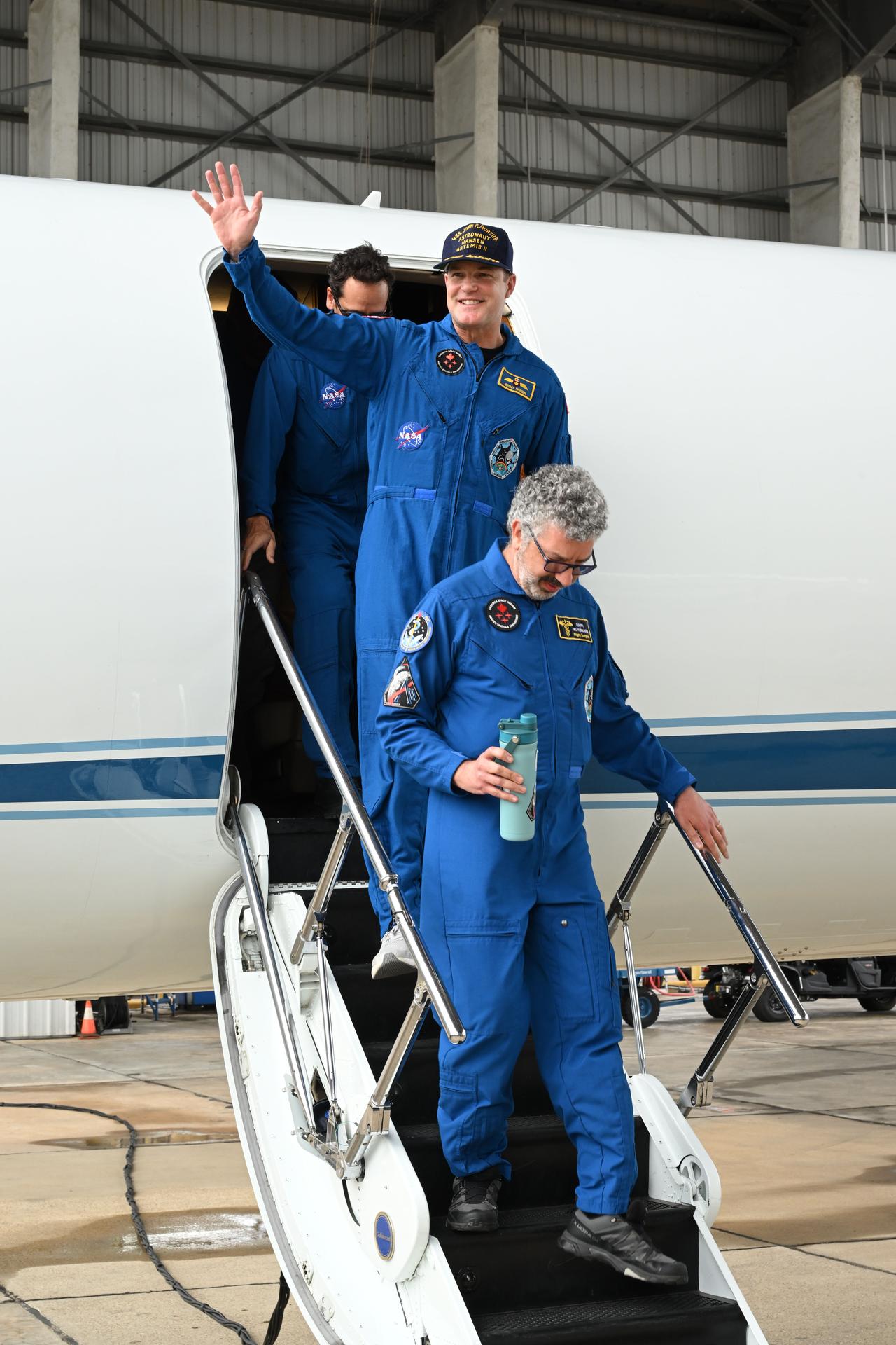 jsc2026e022271 (April 11, 2026) - Artemis II Mission Specialist Jeremy Hansen (center) returns home to Houston, stepping off a plane...