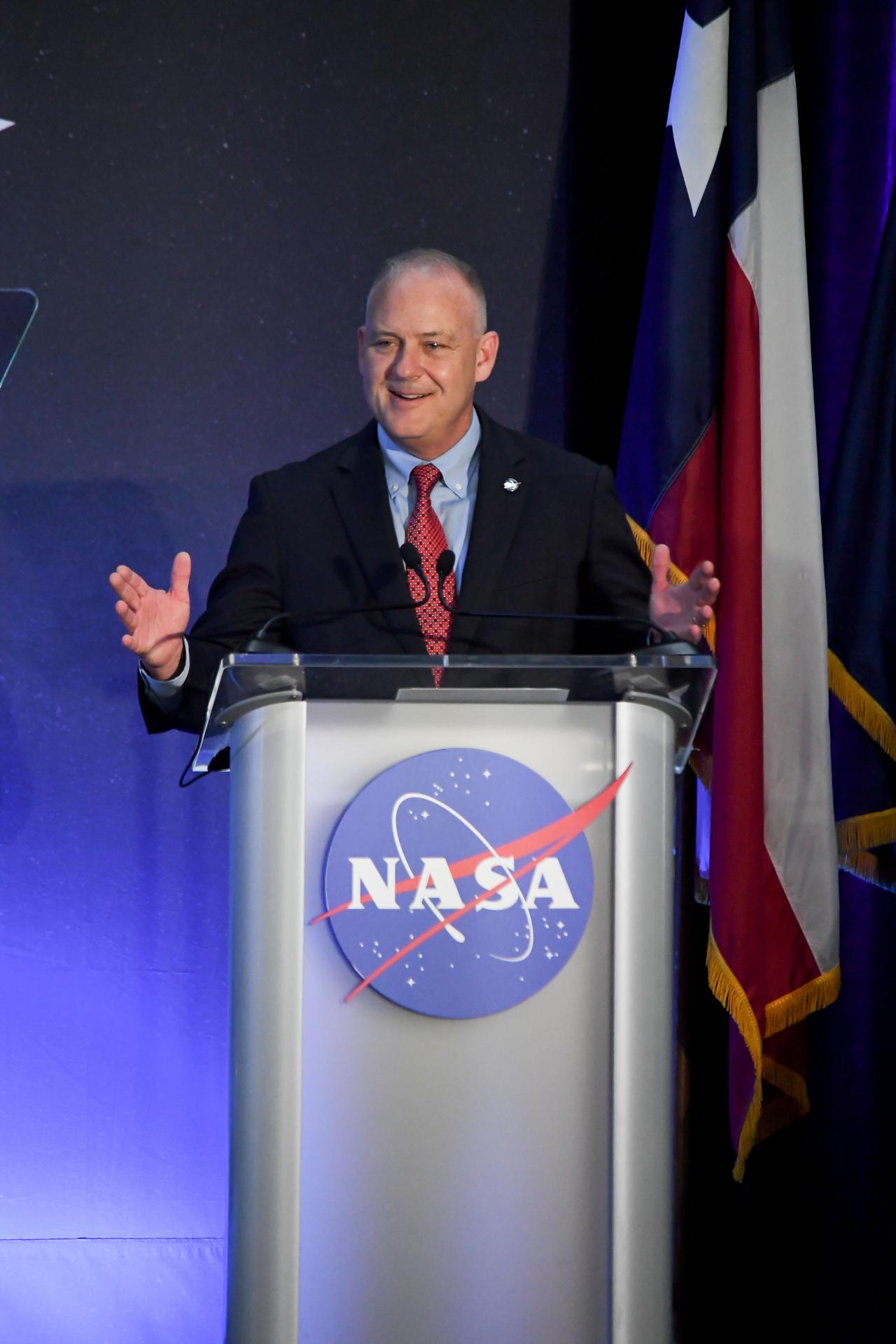 jsc2026e022285 (April 11, 2026) – NASA Flight Operations Director Norm Knight, addresses a crowd of friends, family, and colleagues assembled for the return of the Artemis II crew at Ellington Airport near NASA’s Johnson Space Center in Houston on Saturday, April 11, 2026. The Artemis II test flight launched on Wednesday, April 1, from NASA’s Kennedy Space Center in Florida to begin its 10-day journey around the Moon for scientific discovery, economic benefits, and to build on our foundation for the first crewed missions to Mars. NASA's Orion spacecraft carrying Artemis II Commander Reid Wiseman, Pilot Victor Glover, and Mission Specialist Christina Koch from NASA, along with Mission Specialist Jeremy Hansen from the CSA (Canadian Space Agency), splashed down in the Pacific Ocean near San Diego, California, on Friday, April 10, 2026. Credit: NASA/Bill Stafford