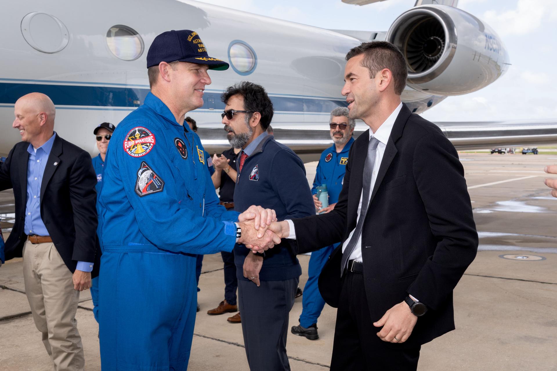 El administrador de la NASA, Jared Isaacman, saluda al especialista de la misión Artemis II, Jeremy Hansen, en el regreso de la tripulación de Artemis II a Houston...