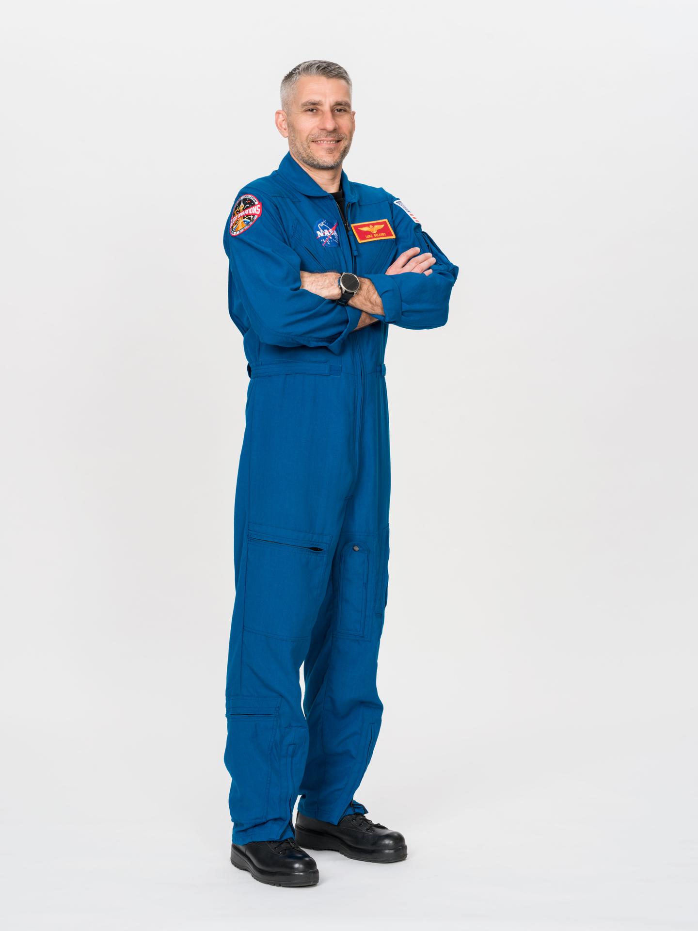 Astronaut Luke Delaney of NASA poses for an official portrait in a blue flight suit at NASA's Johnson Space Center in Houston, Texas. Delaney is serving as pilot for NASA's SpaceX Crew-13 mission to the International Space Station.