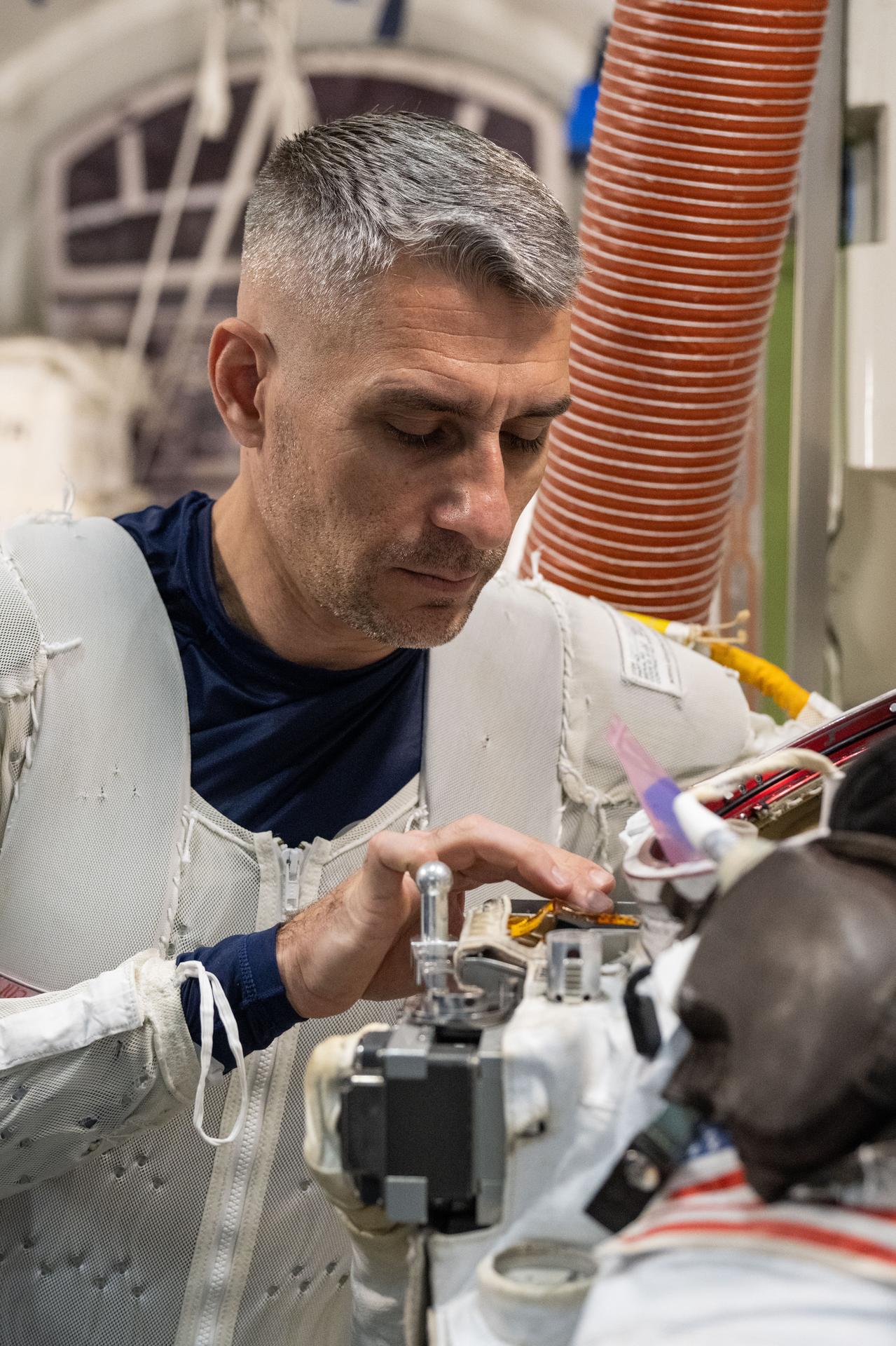 NASA astronaut Luke Delaney practices suiting up in a spacesuit in an International Space Station airlock simulator at Johnson Space Center’s (JSC) Space Vehicle Mockup Facility in Houston, Texas. Astronauts familiarize themselves with spacesuit systems and procedures and practice Quest airlock operations before conducting spacewalk training at JSC’s Neutral Buoyancy Laboratory in simulated microgravity.