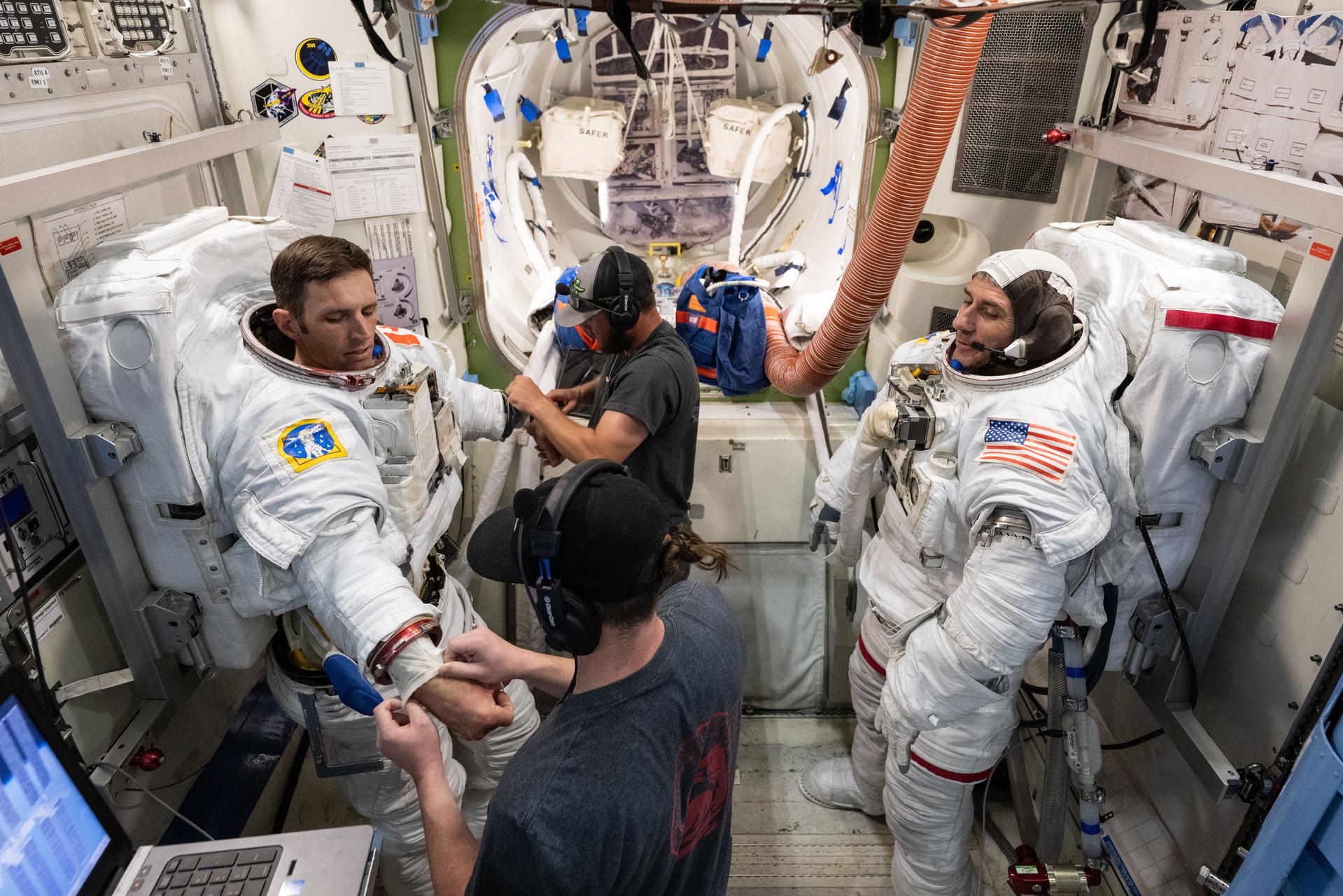 CSA (Canadian Space Agency) astronaut Josh Kutryk (left) and NASA astronaut Luke Delaney (right), with assistance from training specialists, practice suiting up in spacesuits in an International Space Station airlock simulator at Johnson Space Center’s (JSC) Space Vehicle Mockup Facility in Houston, Texas. Astronauts familiarize themselves with spacesuit systems and procedures and practice Quest airlock operations before conducting spacewalk training at JSC’s Neutral Buoyancy Laboratory in simulated microgravity.