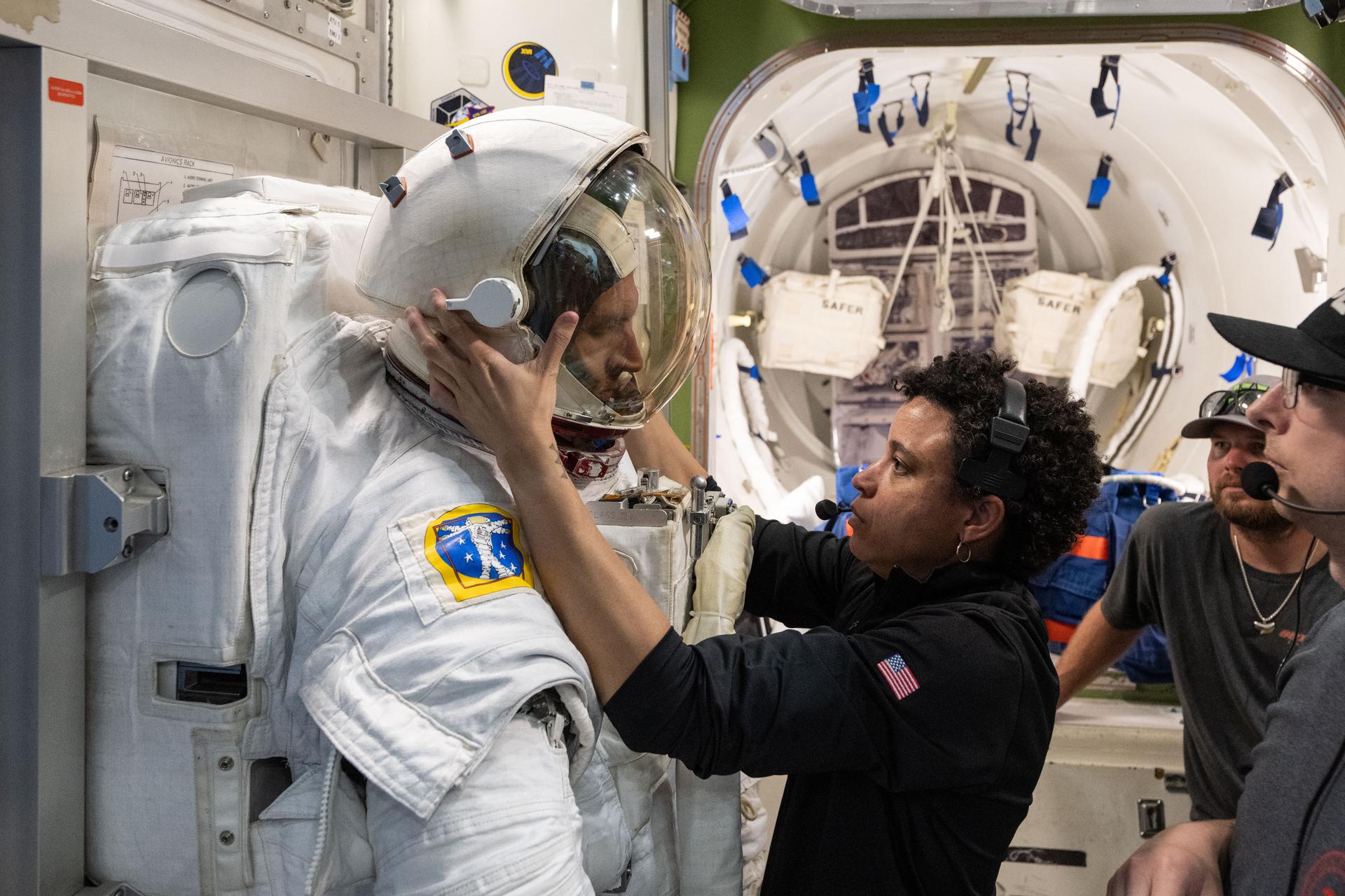 NASA astronaut Jessica Watkins (center), backed up by training specialists, assists CSA (Canadian Space Agency) astronaut Josh Kutryk as he practices suiting up in a spacesuit in an International Space Station airlock simulator at Johnson Space Center’s (JSC) Space Vehicle Mockup Facility in Houston, Texas. Astronauts familiarize themselves with spacesuit systems and procedures and practice Quest airlock operations before conducting spacewalk training at JSC’s Neutral Buoyancy Laboratory in simulated microgravity.
