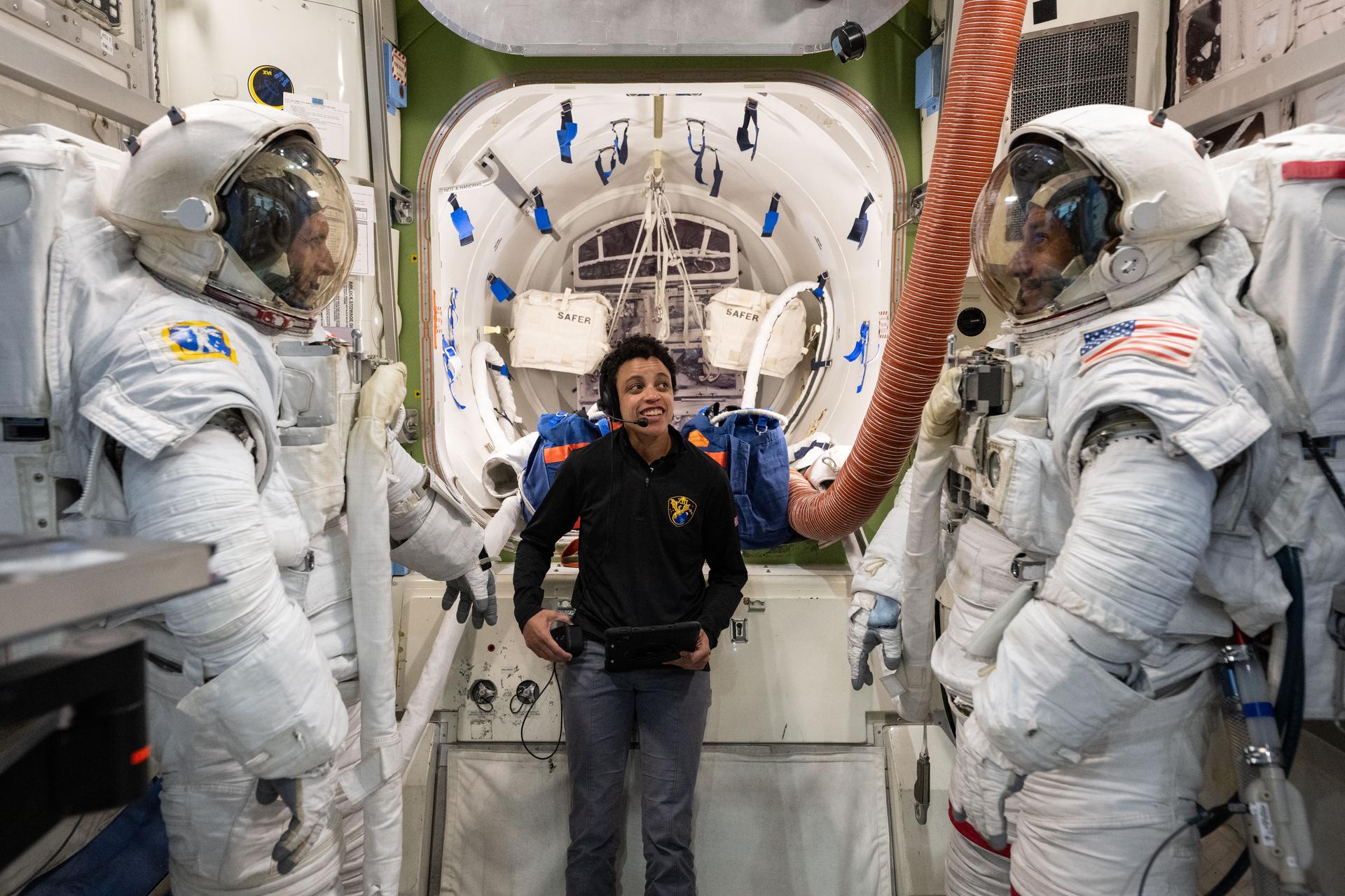 NASA astronaut Jessica Watkins (center) assists CSA (Canadian Space Agency) astronaut Josh Kutryk (left) and NASA astronaut Luke Delaney (right) as they practice suiting up in spacesuits in an International Space Station airlock simulator at Johnson Space Center’s (JSC) Space Vehicle Mockup Facility in Houston, Texas. Astronauts familiarize themselves with spacesuit systems and procedures and practice Quest airlock operations before conducting spacewalk training at JSC’s Neutral Buoyancy Laboratory in simulated microgravity.
