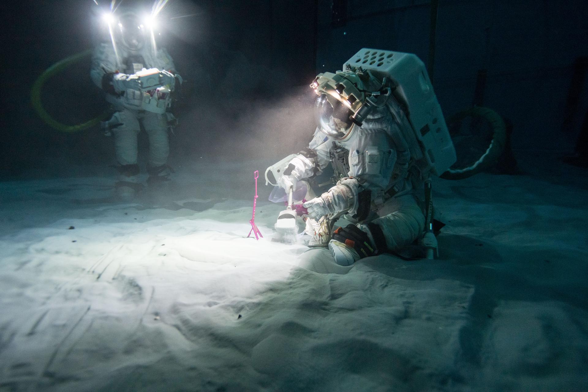 Exploration geologists and Artemis science officers Trevor Graff, left, and Angela Garcia carry out a lunar training development run at NASA’s Neutral Buoyancy Laboratory (NBL) in Houston. The NBL is a 40-foot deep pool at NASA’s Johnson Space Center where astronauts train for spacewalks in a neutrally buoyant environment. During the session, Garcia and Graff conducted tests of Artemis geology tools and deployed a mock lunar payload under low-angle lighting conditions similar to what astronauts will encounter at the Moon’s south pole. A section of the NBL, which contains full-scale mockups of the International Space Station modules, has been transformed into a lunar training area with soil and rocks that mimic the Moon’s landscape. This testing run marked the first time in the Artemis program that two geologists were suited up simultaneously for lunar geology training in the NBL. The team is using insights from these tests to build the training program for astronauts assigned to future landed missions on the Moon. Credit: NASA