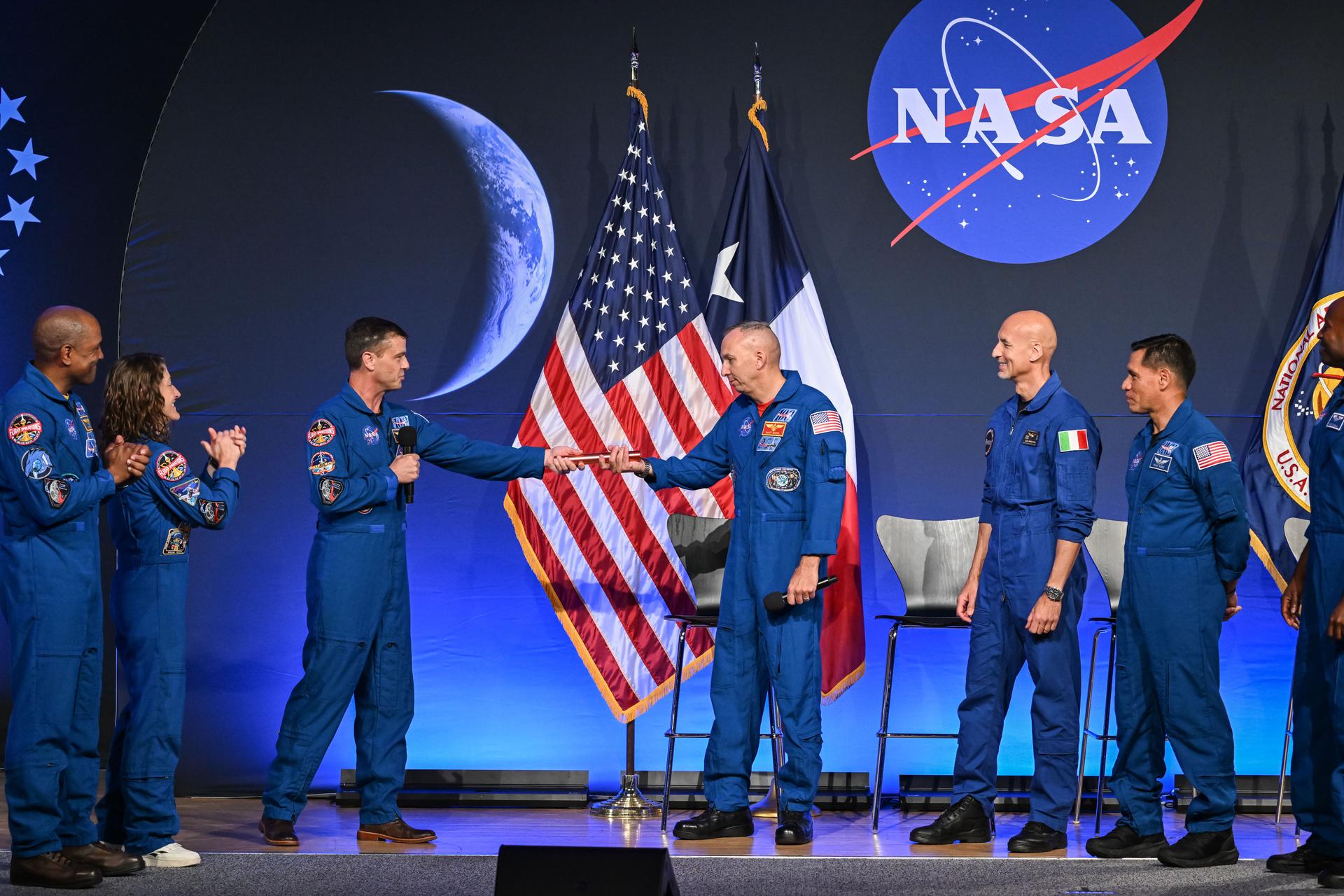 NASA astronauts Victor Glover, Christina Koch, and Reid Wiseman of the Artemis II crew hand a baton to the Artemis III crew (from left: Randy Bresnik, Luca Parmitano, Frank Rubio, Andre Douglas) during an announcement event at NASA's Johnson Space Center in Houston on June 9, 2026. Credit: NASA/Robert Markowitz