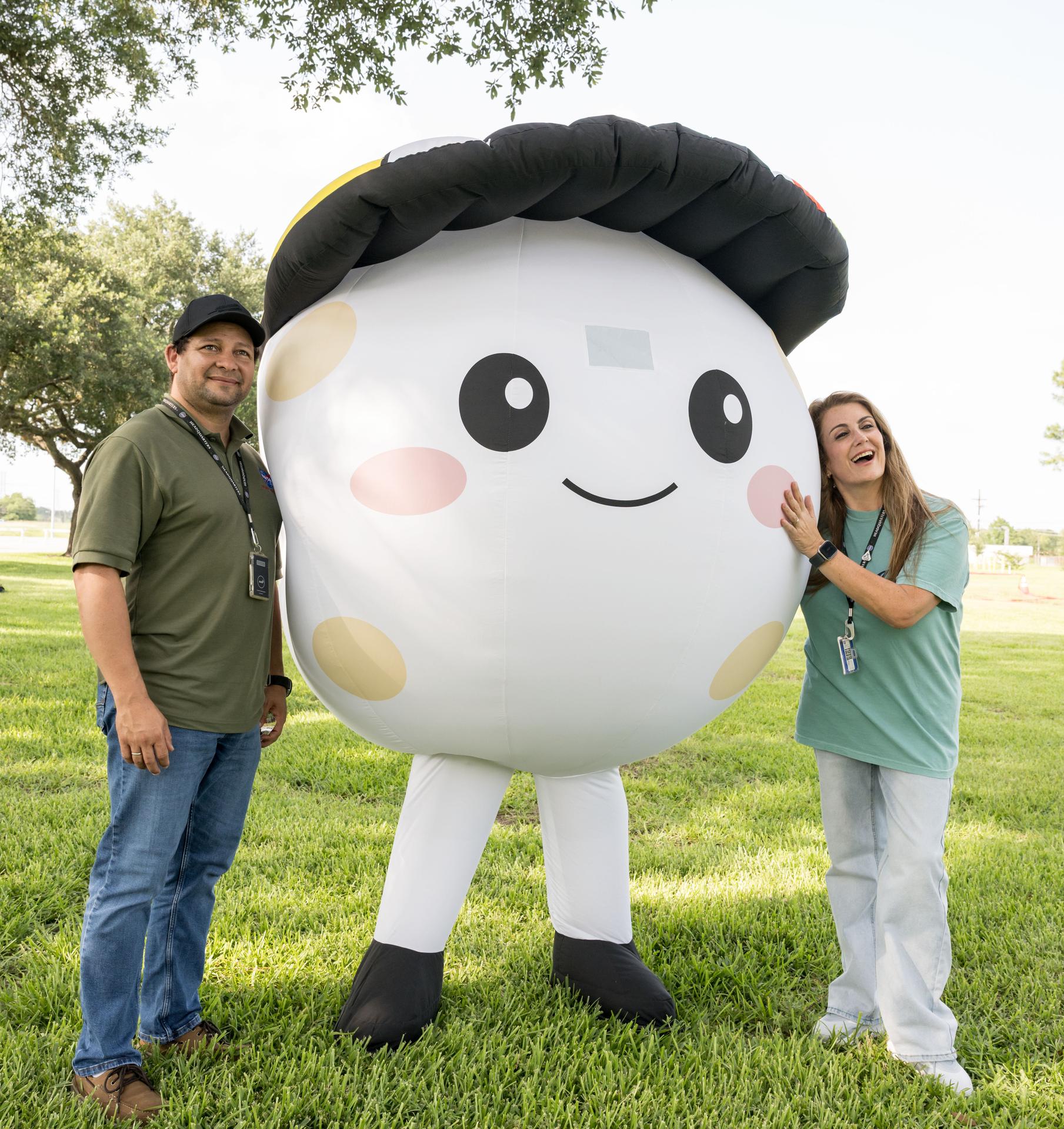 jsc2026e396713 (June 25, 2026) - Attendees pose with Rise, a representation of the zero gravity indicator of the Artemis II mission, during an Artemis II employee celebration event at NASA's Johnson Space Center. Credit: NASA