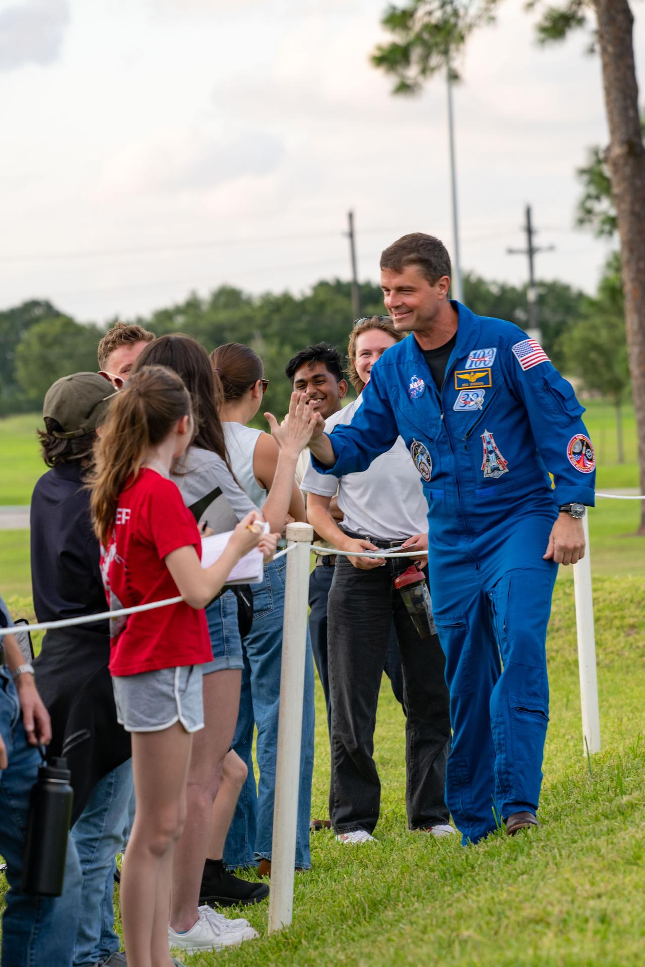 jsc2026e397515 (June 25, 2026) - NASA astronaut Reid Wiseman high-fives attendees at an Artemis II employee celebration event at NASA's Johnson Space Center. Credit: NASA