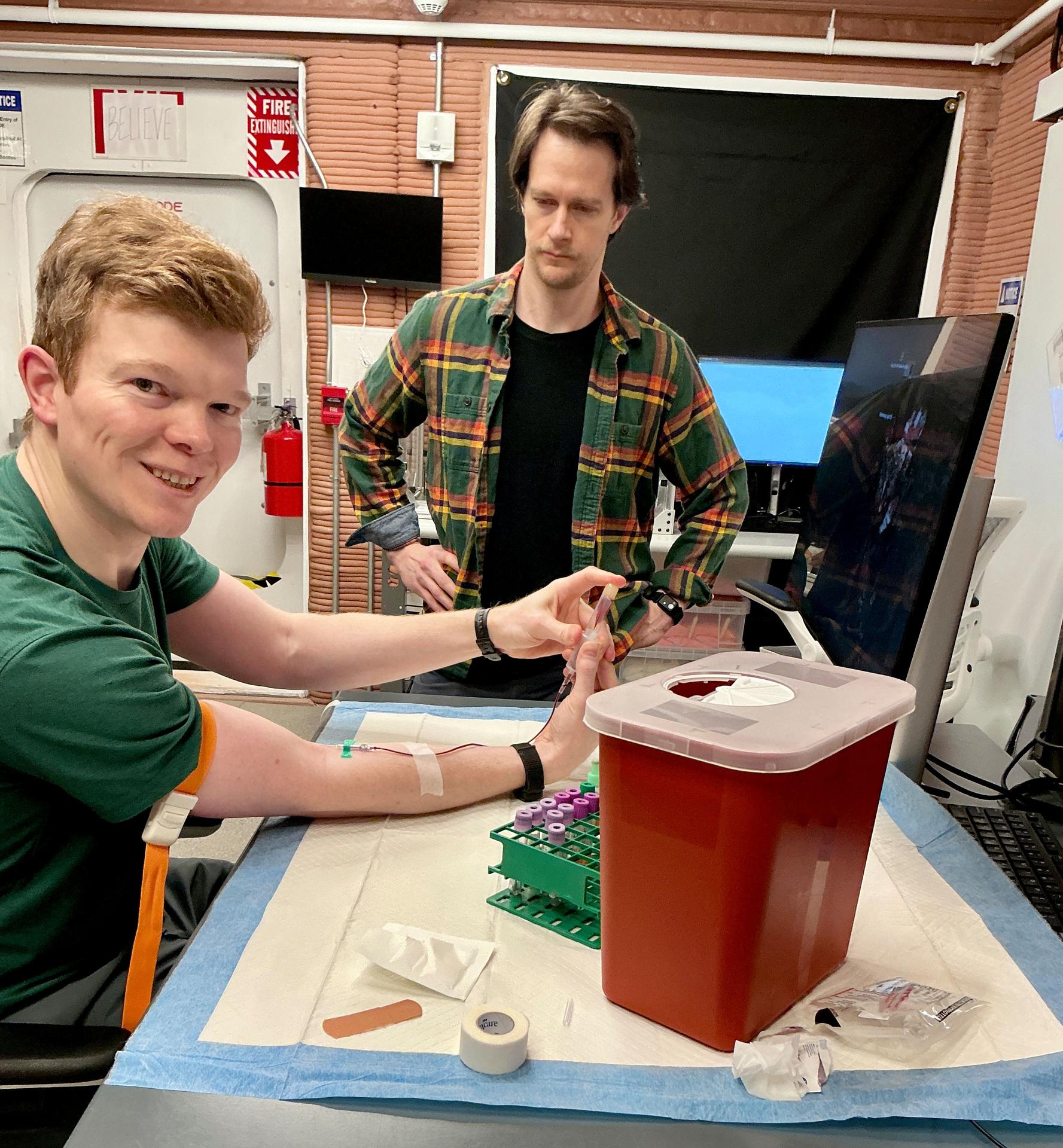 jsc2026e403175 (April 15, 2026) -- CHAPEA crew members perform blood collections to monitor their health (From left: James Spicer, Matthew Montgomery). Credit: NASA