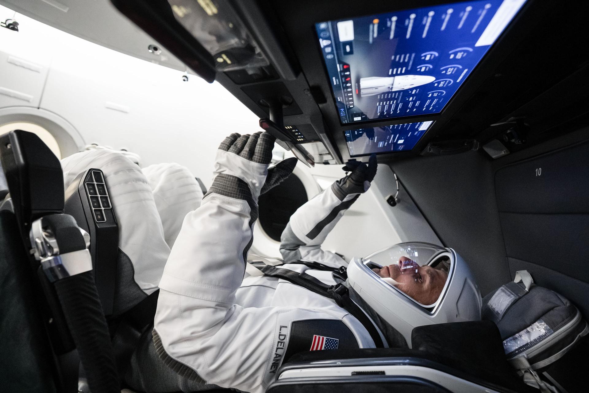 NASA astronaut and SpaceX Crew‑13 Pilot Luke Delaney sits inside a Dragon spacecraft mockup while tapping a cockpit screen interface during a pre‑flight training session at SpaceX headquarters in Hawthorne, California.