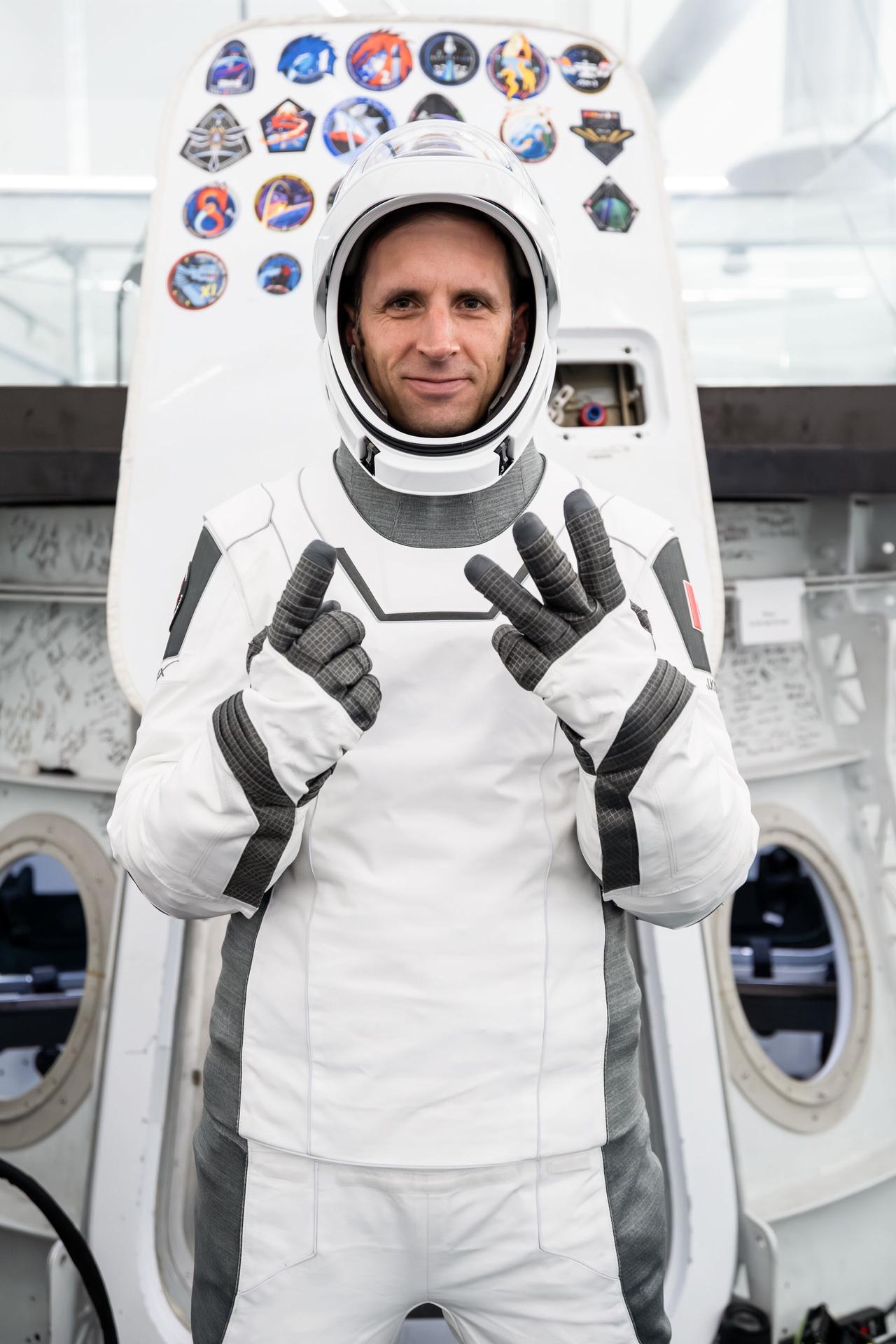 CSA (Canadian Space Agency) astronaut and SpaceX Crew-13 Mission Specialist Joshua Kutryk gestures with his fingers to show the number 13, representing his mission to the International Space Station aboard a Dragon spacecraft. Kutryk poses in his pressure suit in front of a Dragon spacecraft mockup during a pre-flight training session at SpaceX headquarters in Hawthorne, California.