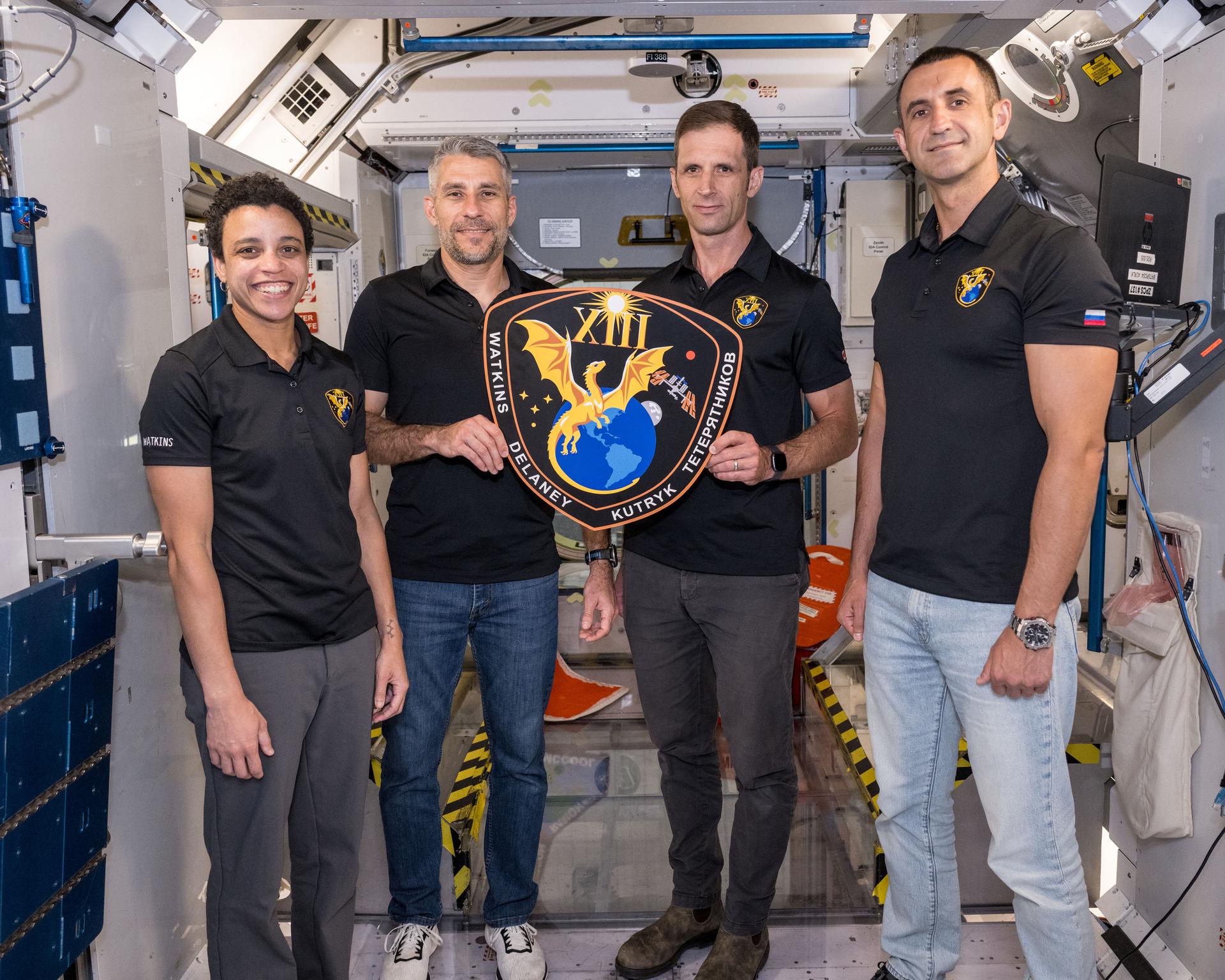 The four members of NASA's SpaceX Crew-13 mission to the International Space Station display their mission plaque inside a training mockup of a space station module. From left are, Commander Jessica Watkins and Pilot Luke Delaney, both from NASA, and Mission Specialists Joshua Kutryk of CSA (Canadian Space Agency) and Sergey Teteryatnikov of Roscosmos.