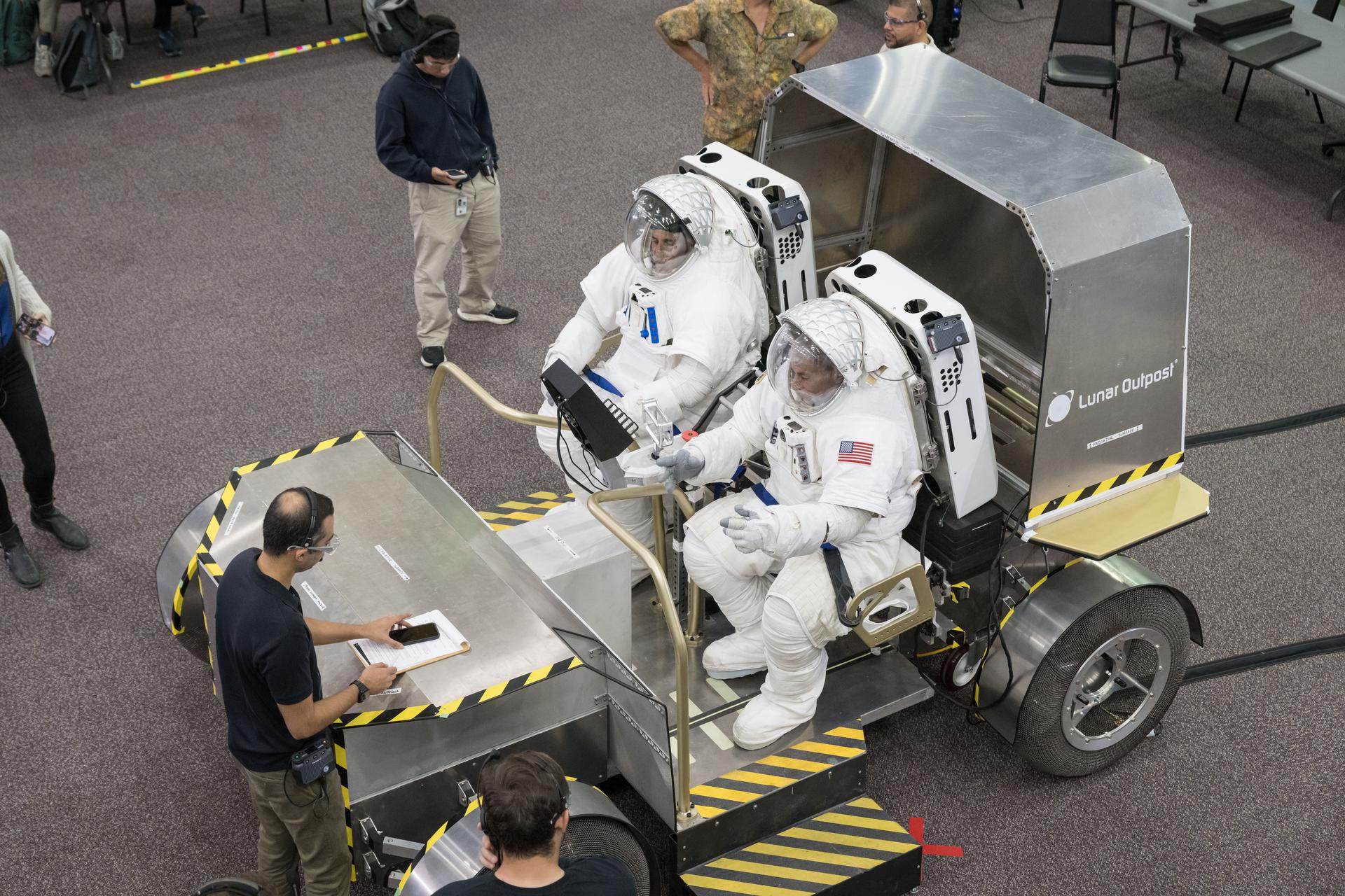 NASA astronauts Joe Acaba (left) and Mark Vande Hei (right) sit inside Lunar Outpost’s Pegasus lunar terrain vehicle prototype during human-in-the-loop testing at NASA’s Johnson Space Center where they evaluated the design, usability, and crew comfort of Lunar Outpost’s lunar rover. NASA selected Lunar Outpost and Astrolab in May 2026 to build and deliver the first phase of lunar terrain vehicles for Moon Base development. Image Credit: NASA/Bill Stafford