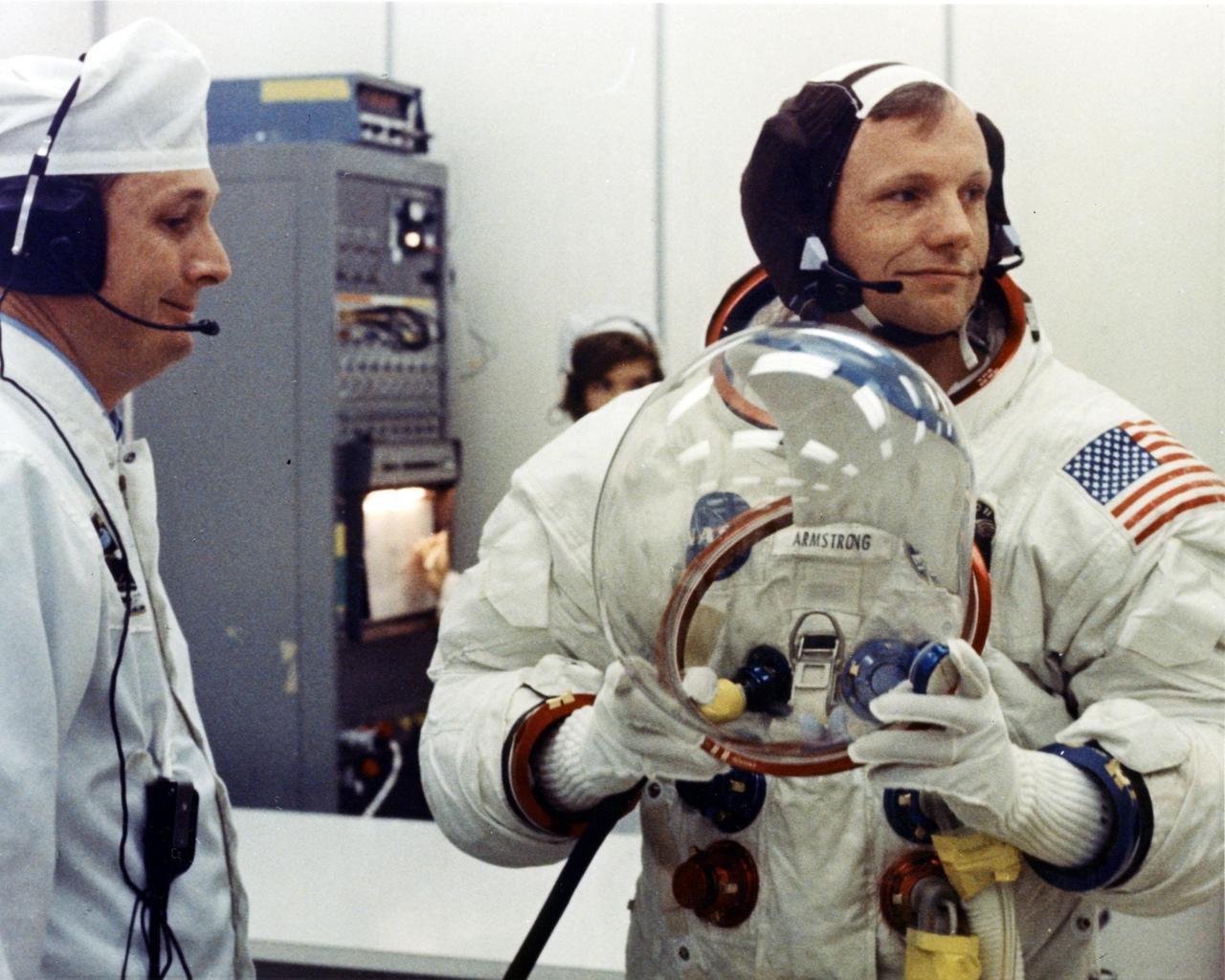 Apollo 11 Commander Neil Armstrong prepares to put on his helmet with the assistance of a spacesuit technician during suiting operations in the Manned Spacecraft Operations Building (MSOB) prior to the astronauts' departure to Launch Pad 39A. The three astronauts, Edwin E. Aldrin Jr., Neil A Armstrong and Michael Collins, will then board the Saturn V launch vehicle, scheduled for a 9:32 a.m. EDT liftoff, for the first manned lunar landing mission