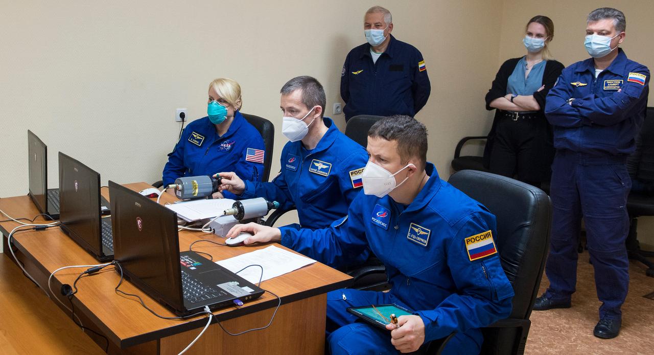 nhq202010060003 (Oct. 6, 2020) --- Expedition 64 crew members NASA astronaut Kate Rubins, left, and Russian cosmonauts Sergey Ryzhikov, center, and Sergey Kud-Sverchkov, right, of Roscosmos practice rendezvous techniques on a laptop simulator, Tuesday, Oct. 6, 2020, at the Cosmonaut Hotel in Baikonur, Kazakhstan. The trio are scheduled to launch to the International Space Station aboard the Soyuz MS-17 spacecraft on October 14. Photo Credit: (NASA/GCTC/Andrey Shelepin)