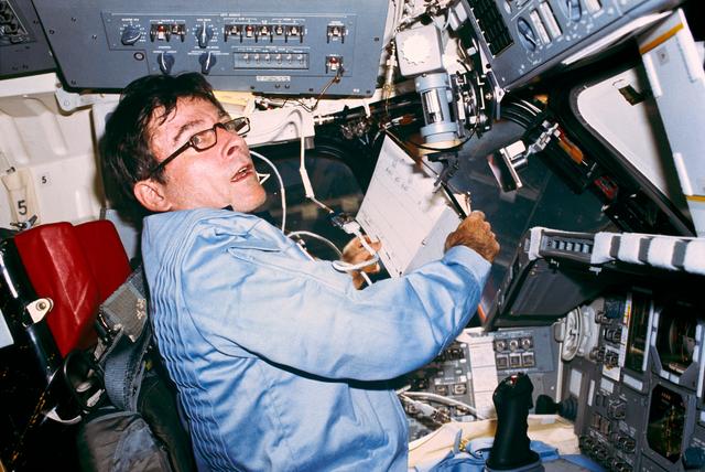 NASA image: Commander Young reviews clipboard notes and procedures on forward flight deck