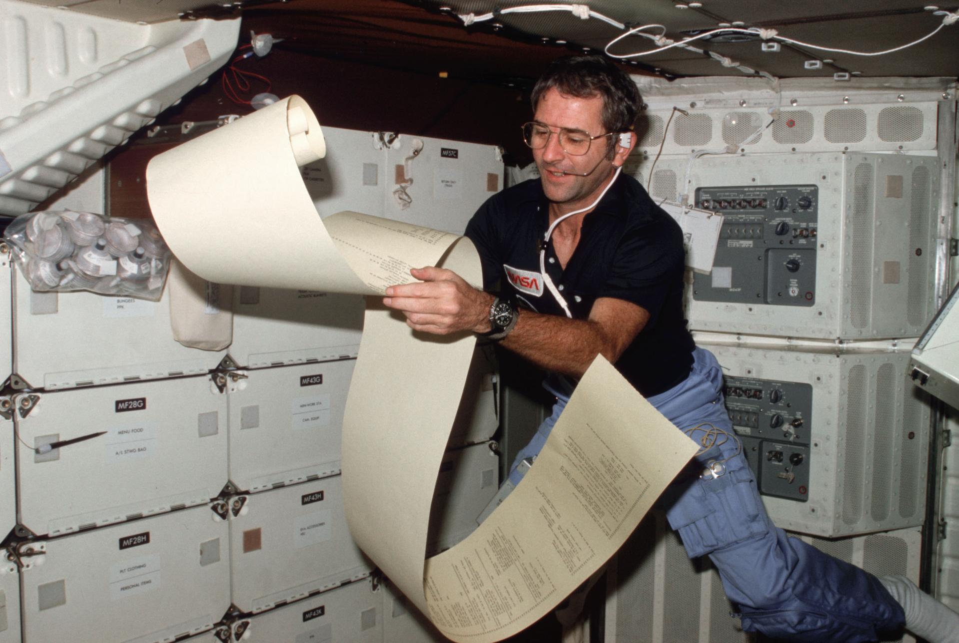 Richard Truly floats in the middeck area of Space Shuttle Columbia reading teleprinter copy for STS-2