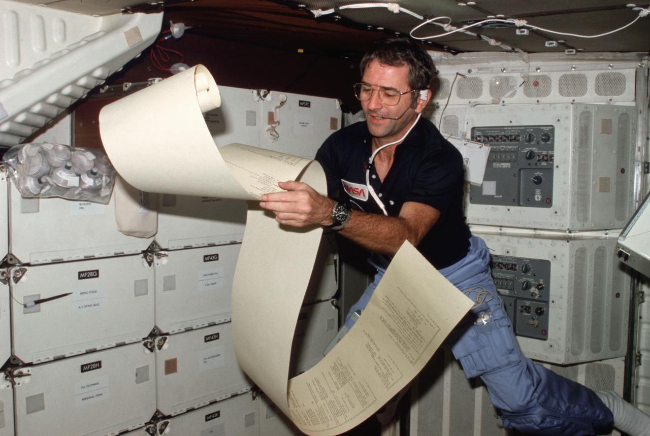 STS002-02-865 (12-14 Nov. 1981) --- Astronaut Richard H. Truly, STS-2 pilot, peruses some teleprinter copy, floating partially about the middeck area of NASA’s space shuttle Columbia during one of 1,813 minutes of activity of STS-2. This photograph was recorded with 35mm camera in the hands of astronaut Joe H. Engle, STS-2 crew commander. Truly communicates with spacecraft communicators on the ground. Photo credit: NASA