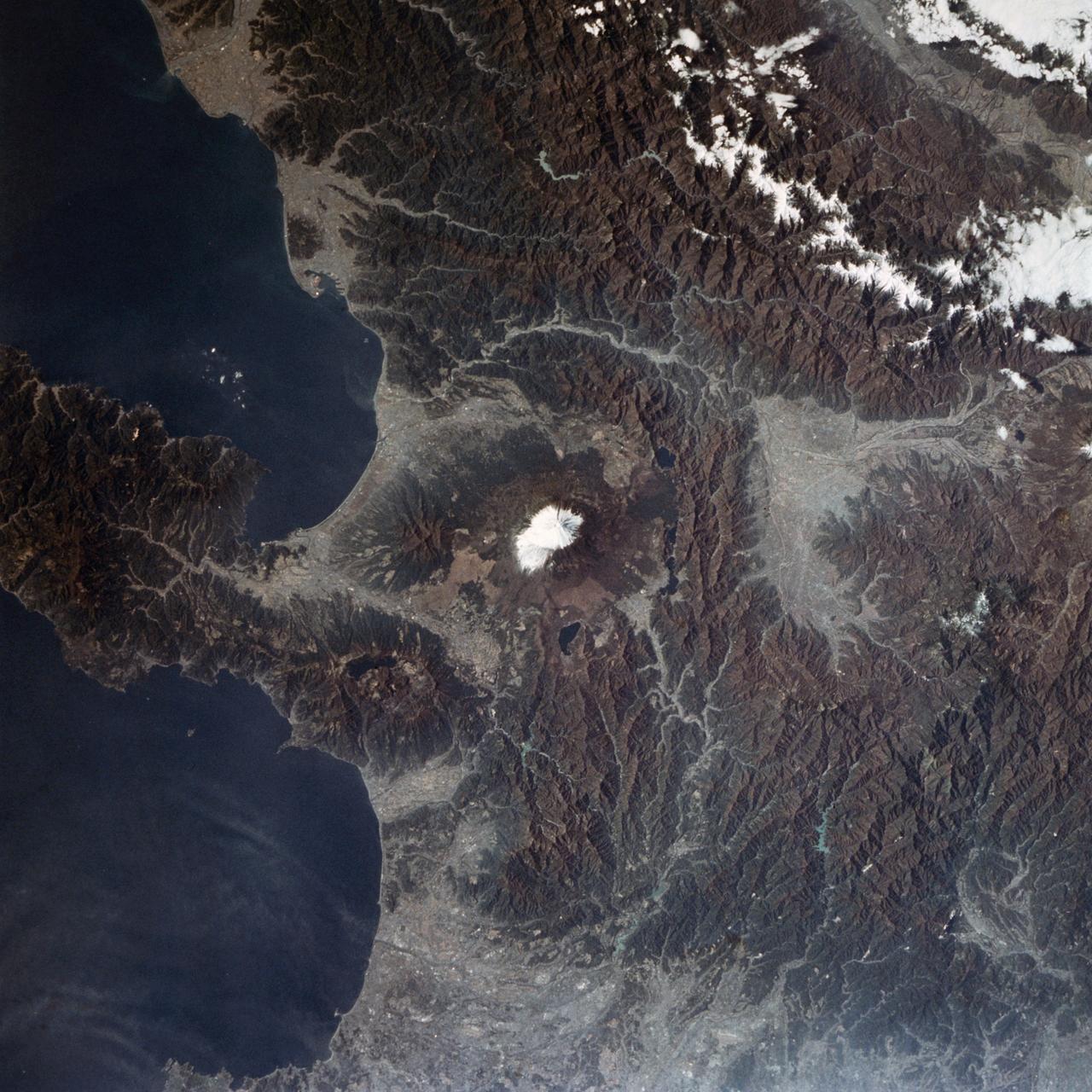 STS002-09-391A (12-14 Nov. 1981) --- Honshu Island, Japan, and its snow-covered Fuji-San or Fuji-Yama volcano are the features of this 70mm frame. The volcano peak is 12,400 feet tall. The western suburbs of Tokyo are at right edge of the photograph. Isu Peninsula is at the bottom, separating the Suruga and Sagami Bays. Other large cities include Yokohama, Kozu, Shizuoka, Namazu and Odawara. Photo credit: NASA