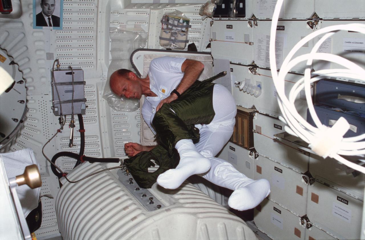 STS003-23-161 (24 March 1982) --- Astronaut C. Gordon Fullerton, STS-3 pilot, dons an olive drab inner garment which complements the space shuttle Extravehicular Mobility Unit (EMU) spacesuit. Since there are no plans for an extravehicular activity (EVA) on the flight, Fullerton is just getting some practice time ?in the field? as he is aboard the Earth-orbiting Columbia. He is in the middeck area of the vehicle. The photograph was taken with a 35mm camera by astronaut Jack R. Lousma, STS-3 commander. Photo credit: NASA