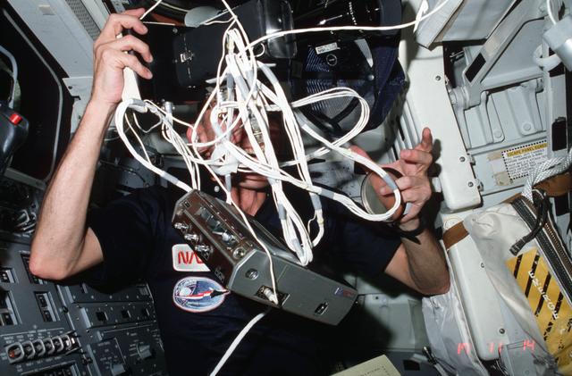 NASA image: Commander Mattingly tangles with NOSL experiment on aft flight deck