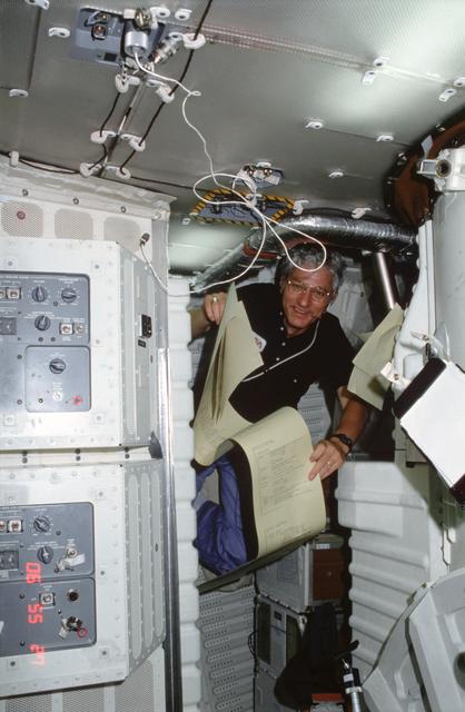 NASA image: Pilot Hartsfield reviews TAGS teleprinter printout of instructions on middeck